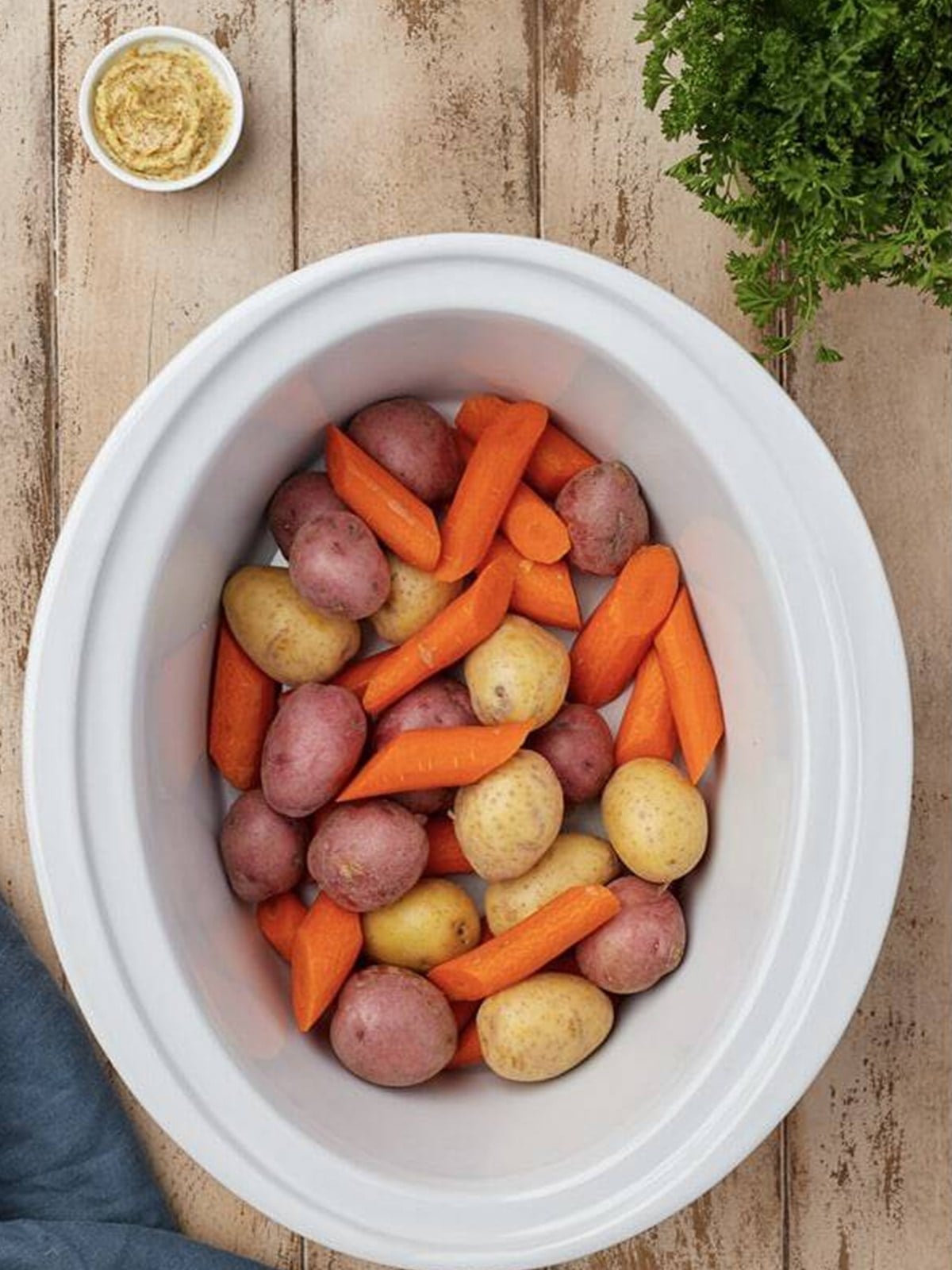 Baby potatoes and carrots in the bottom of a slow cooker.