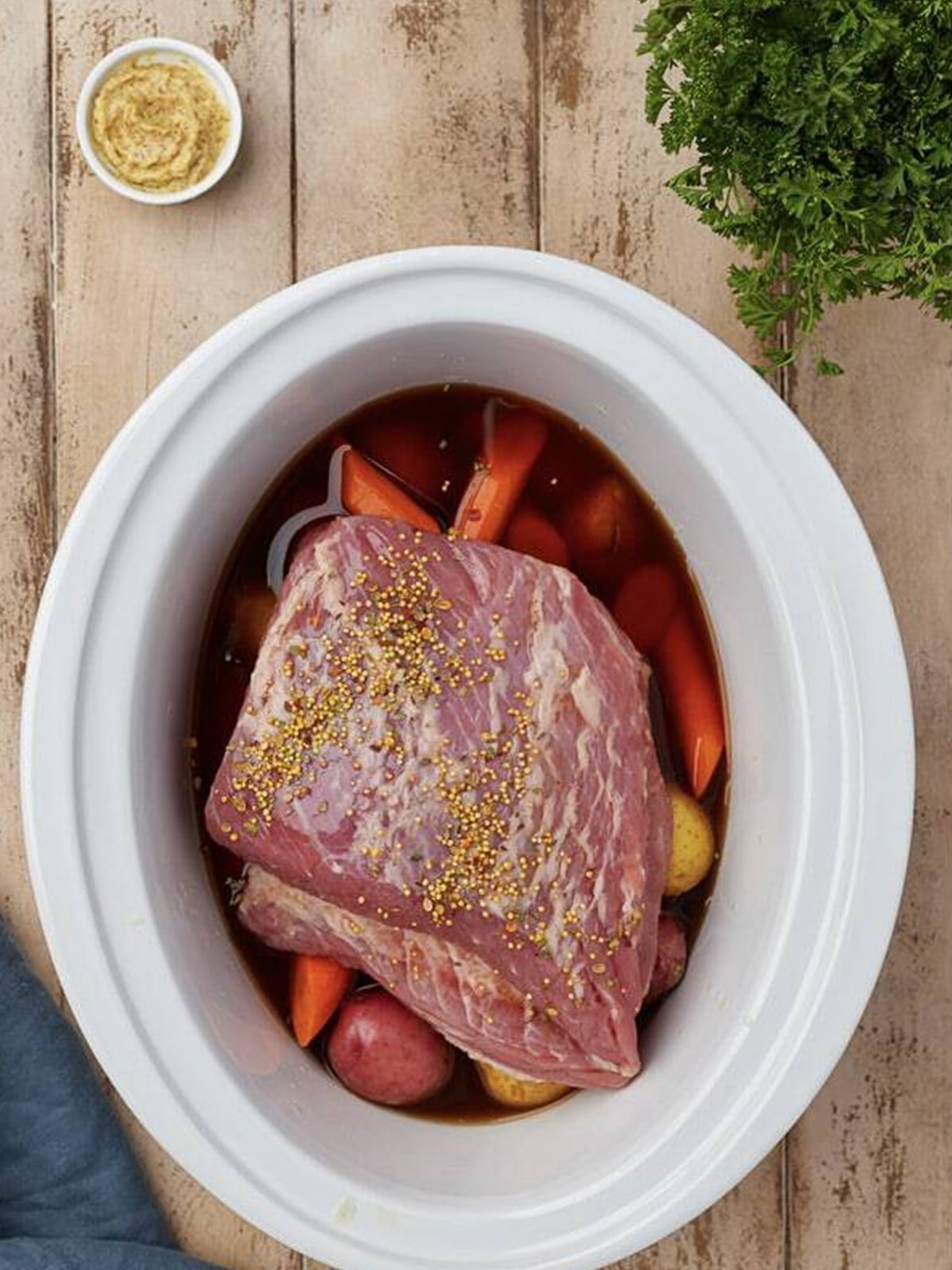 Beef broth and pickling spices poured over the corned beef in the slow cooker.
