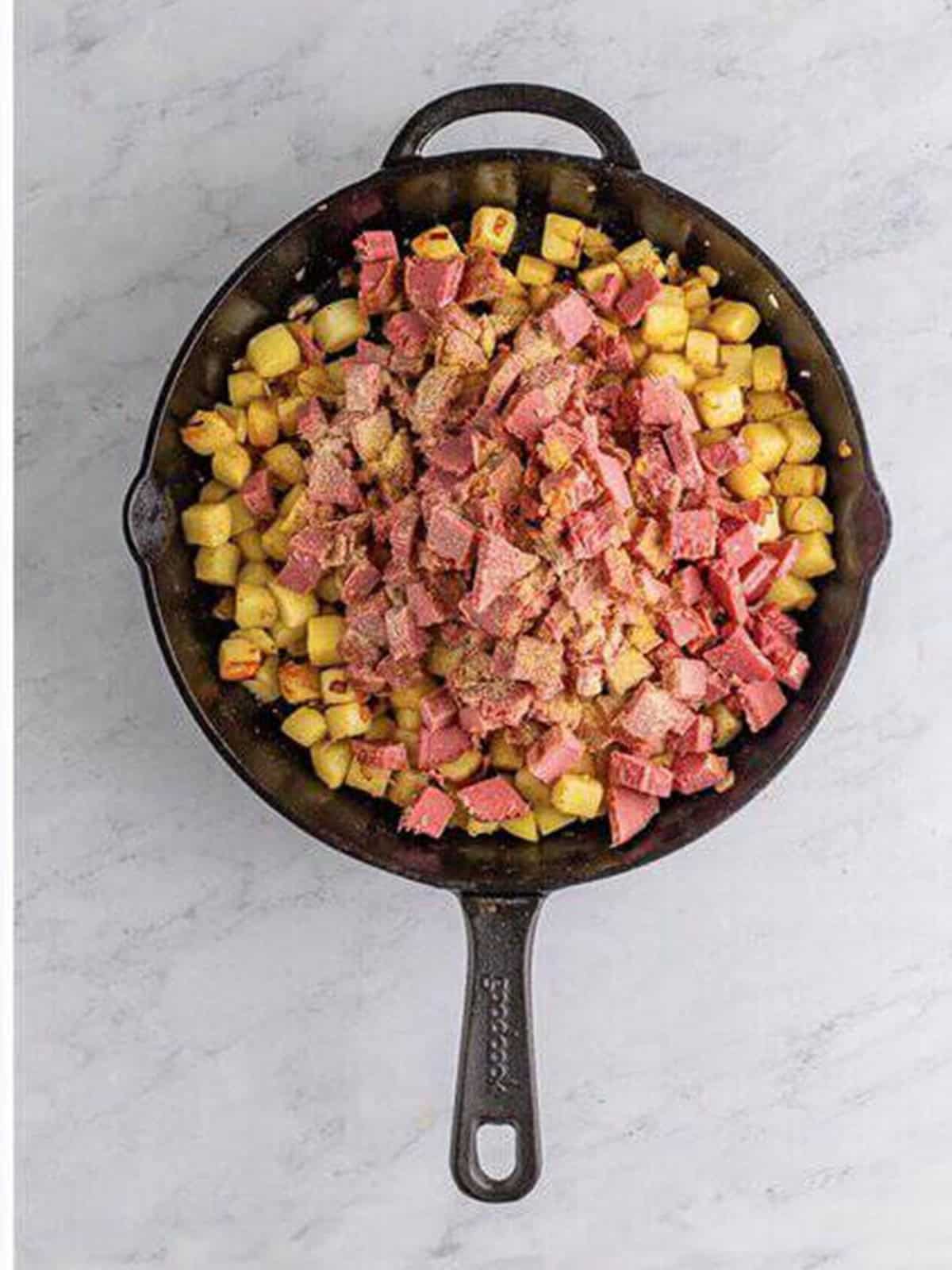 Cooked corned beef added to the potatoes and onions for homemade corned beef hash.