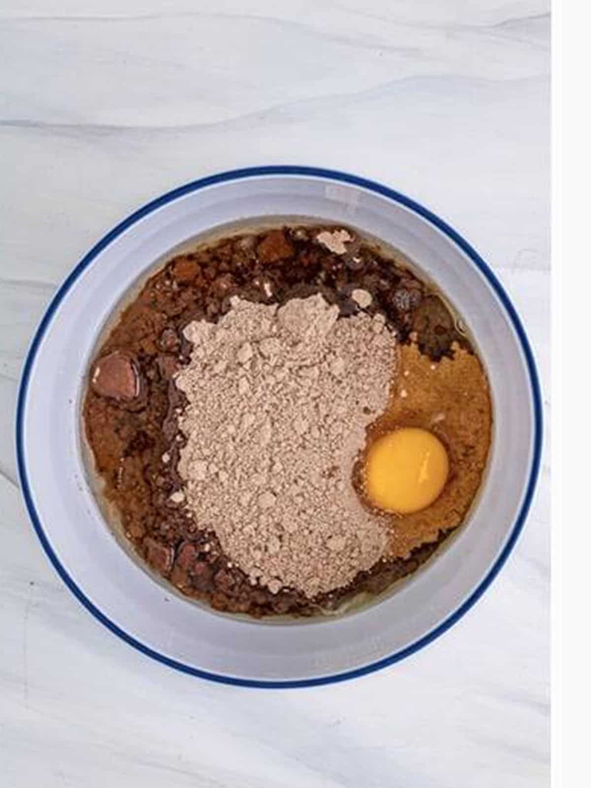Mixing brownie mix, oil, and egg into a thick cookie dough in a glass bowl.