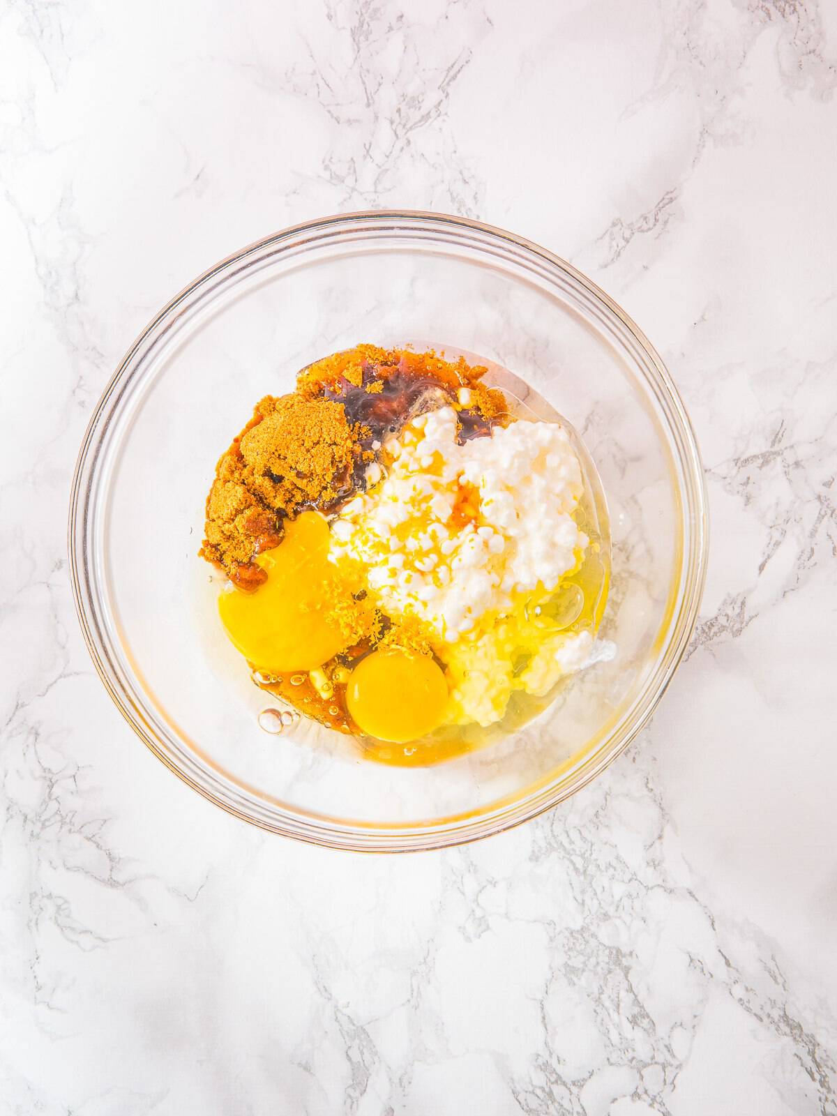 Cottage cheese, eggs, honey, and oil mixed in a bowl for Cottage Cheese Blueberry Muffins.