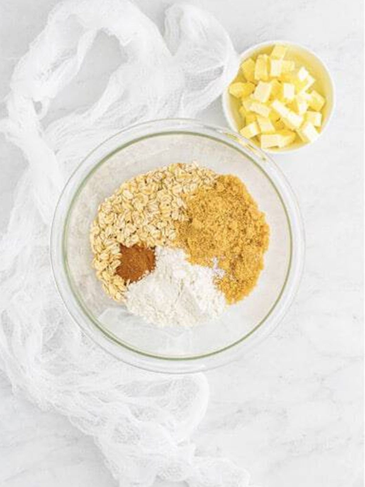 Rolled oats, flour, brown sugar, cinnamon, and butter in a glass bowl for the crack pie crust.