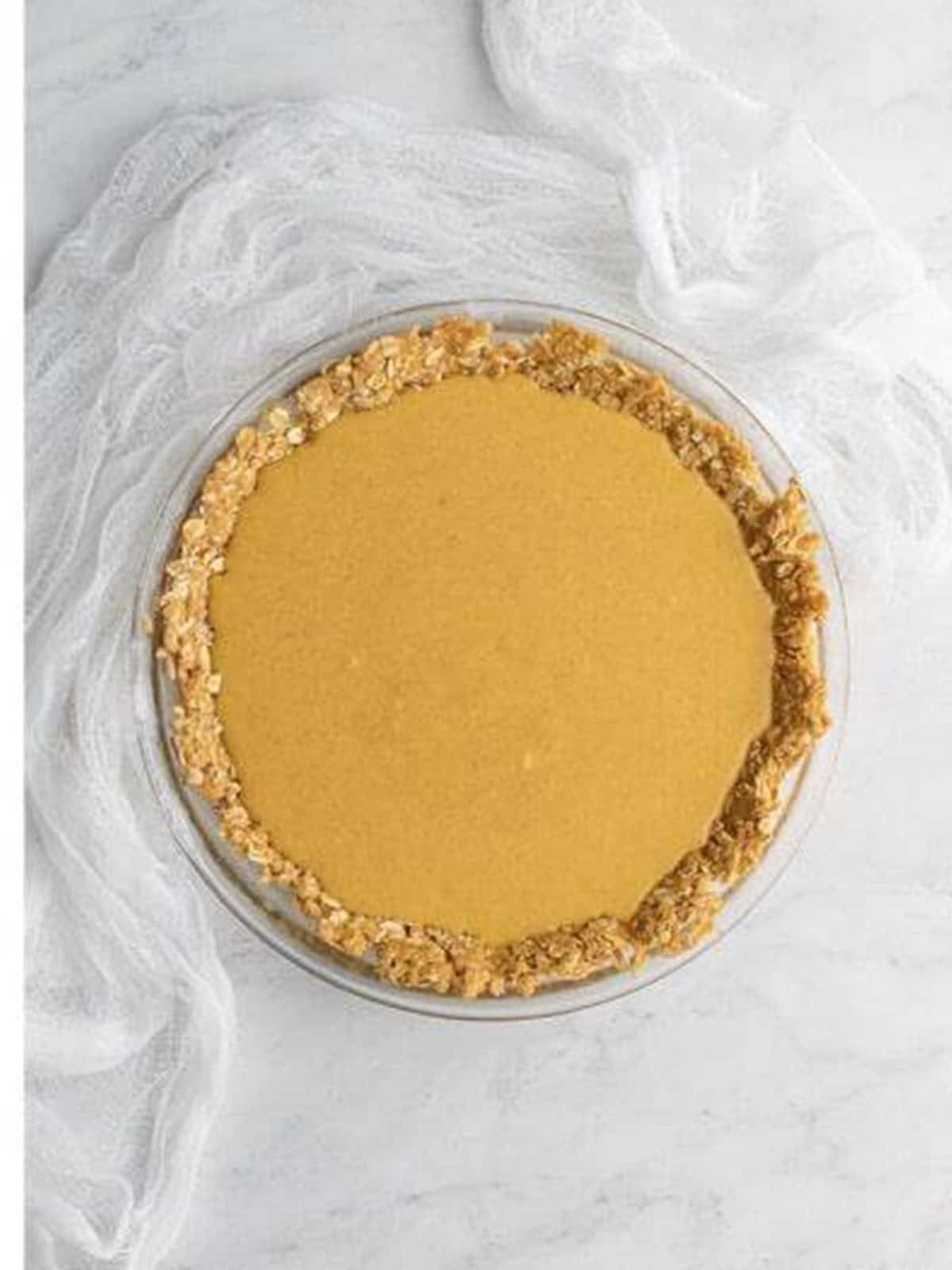 Smooth crack pie filling poured into the oat cookie crust before baking.