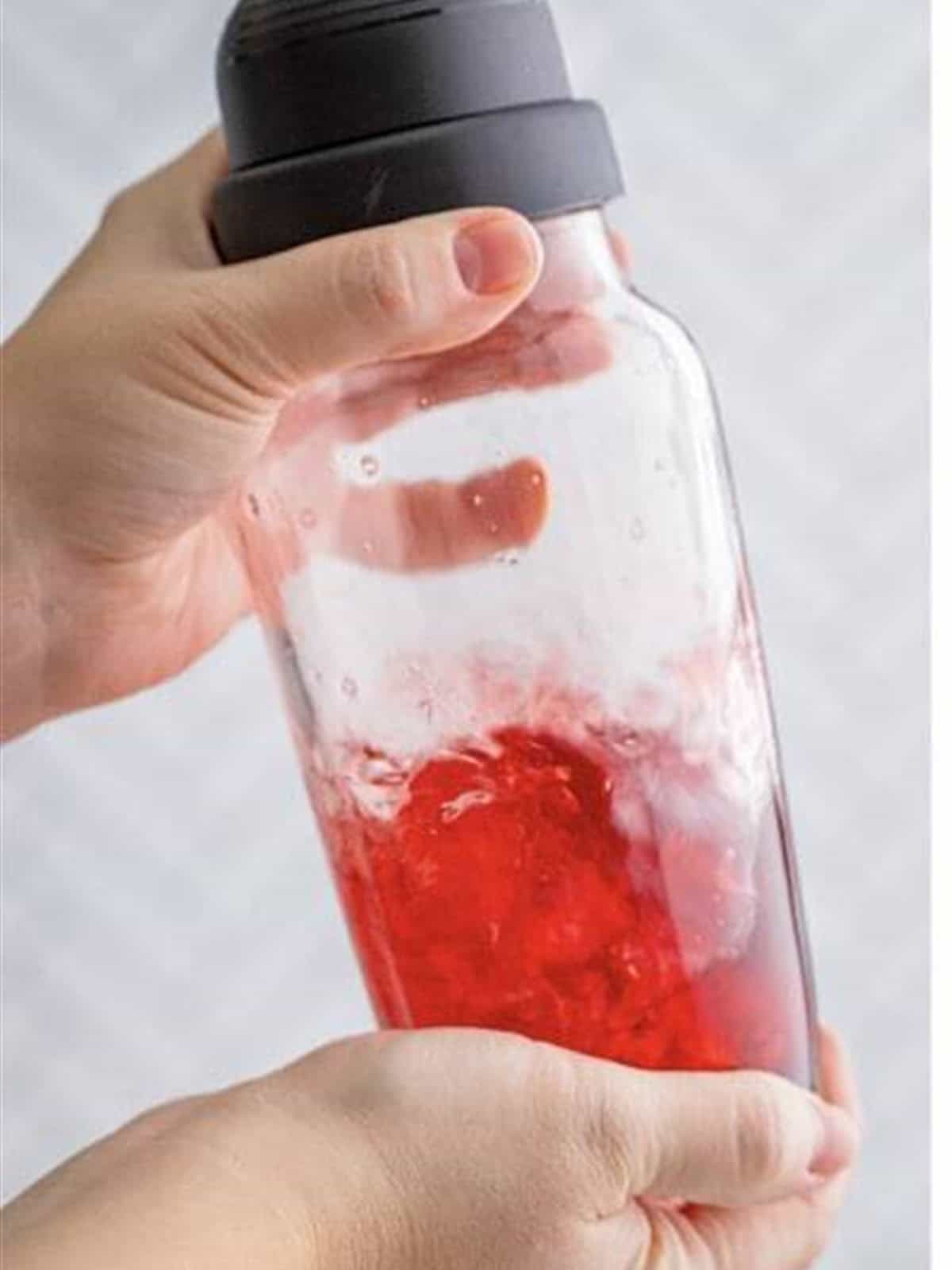 The cocktail shaker filled and being shaken with ice.