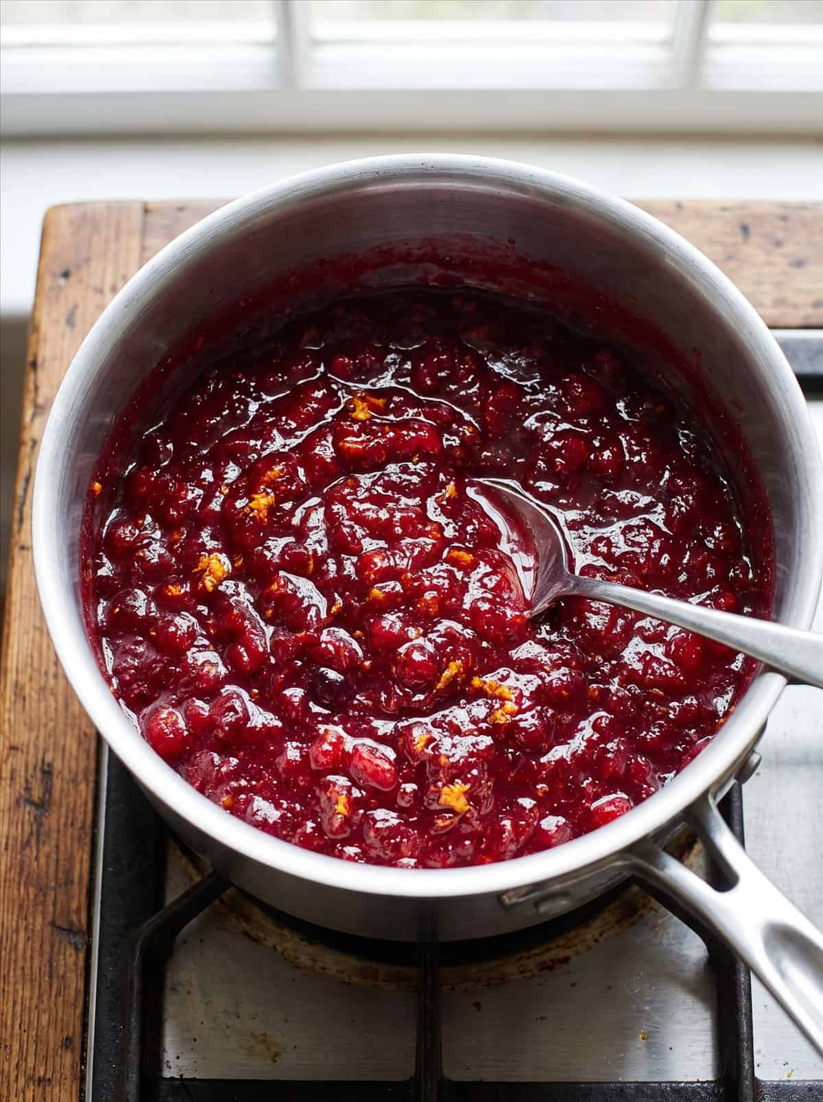 Finished thick glossy homemade cranberry sauce in a saucepan.