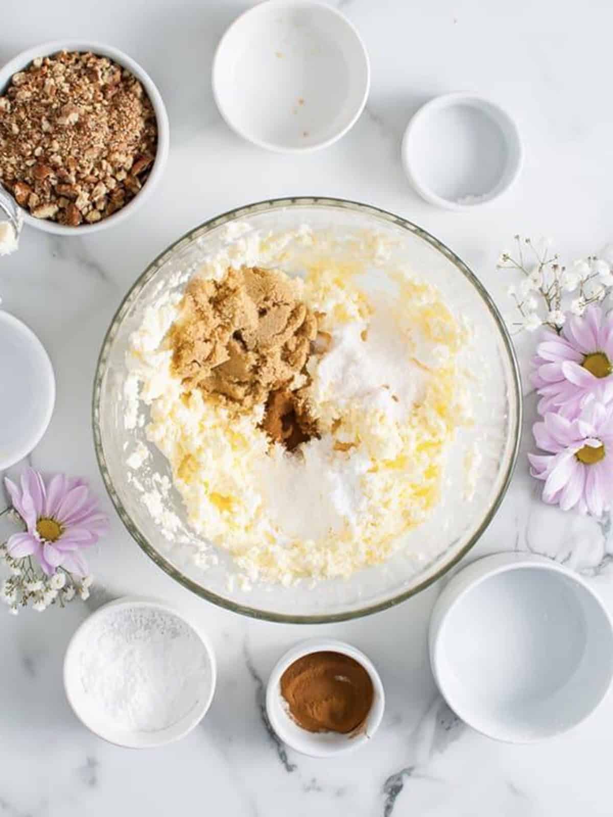 Cream cheese, butter, powdered sugar, brown sugar, pudding mix, and cinnamon added to a glass bowl for a cream cheese ball.