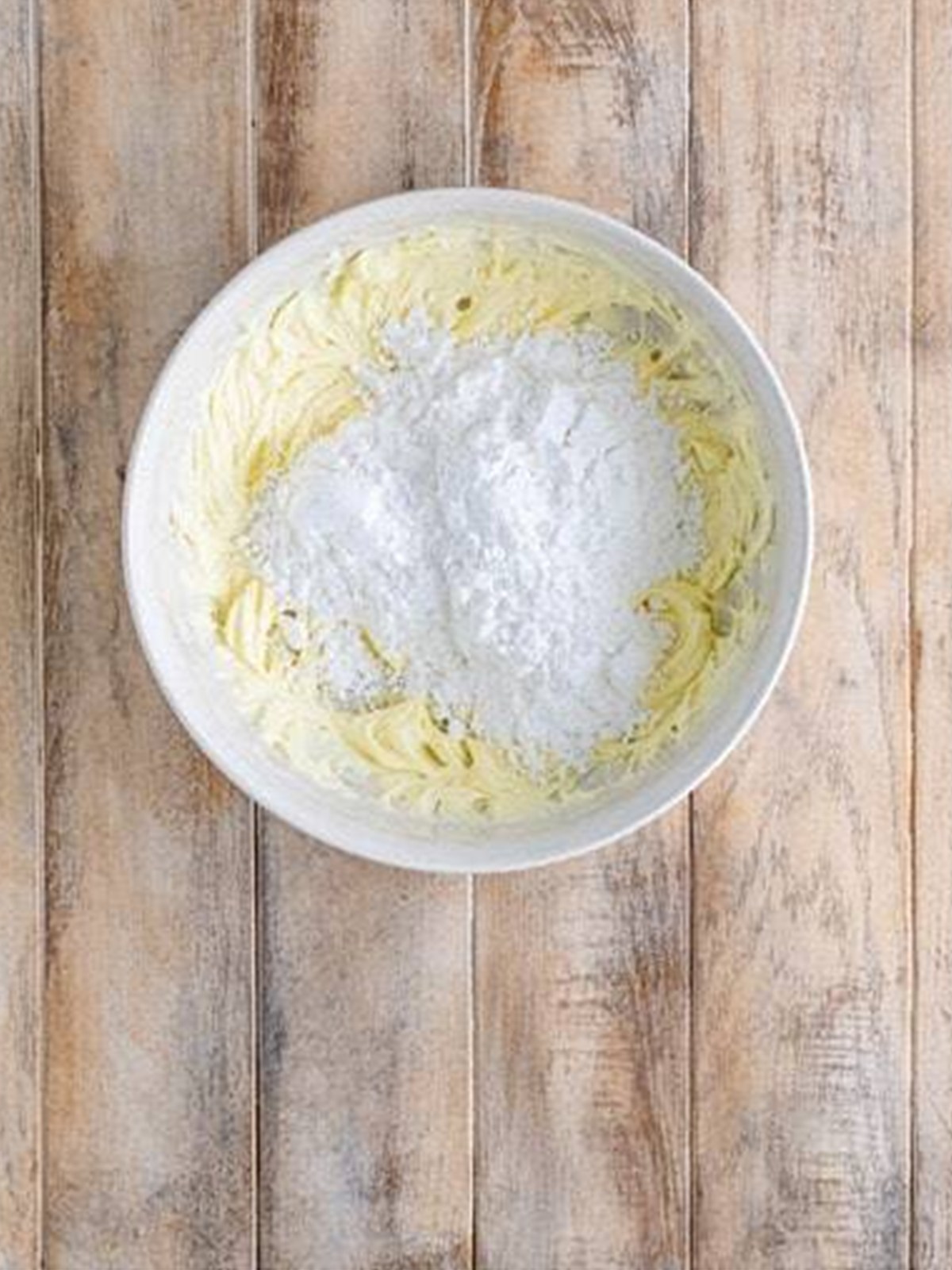 Creaming cream cheese, butter, and powdered sugar in a bowl for cookie dough.