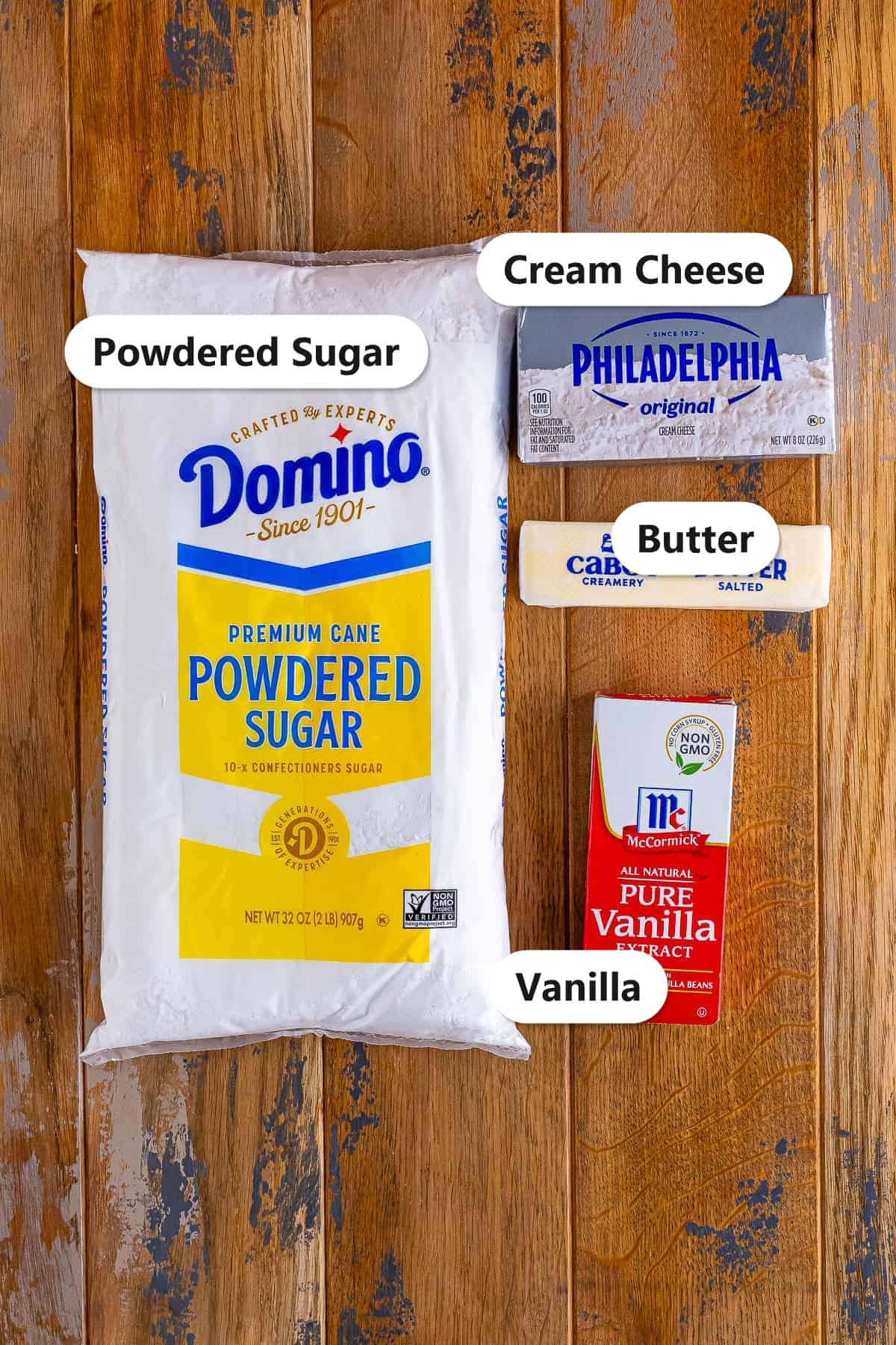 Labeled ingredients for cream cheese frosting including powdered sugar, cream cheese, butter, and vanilla.