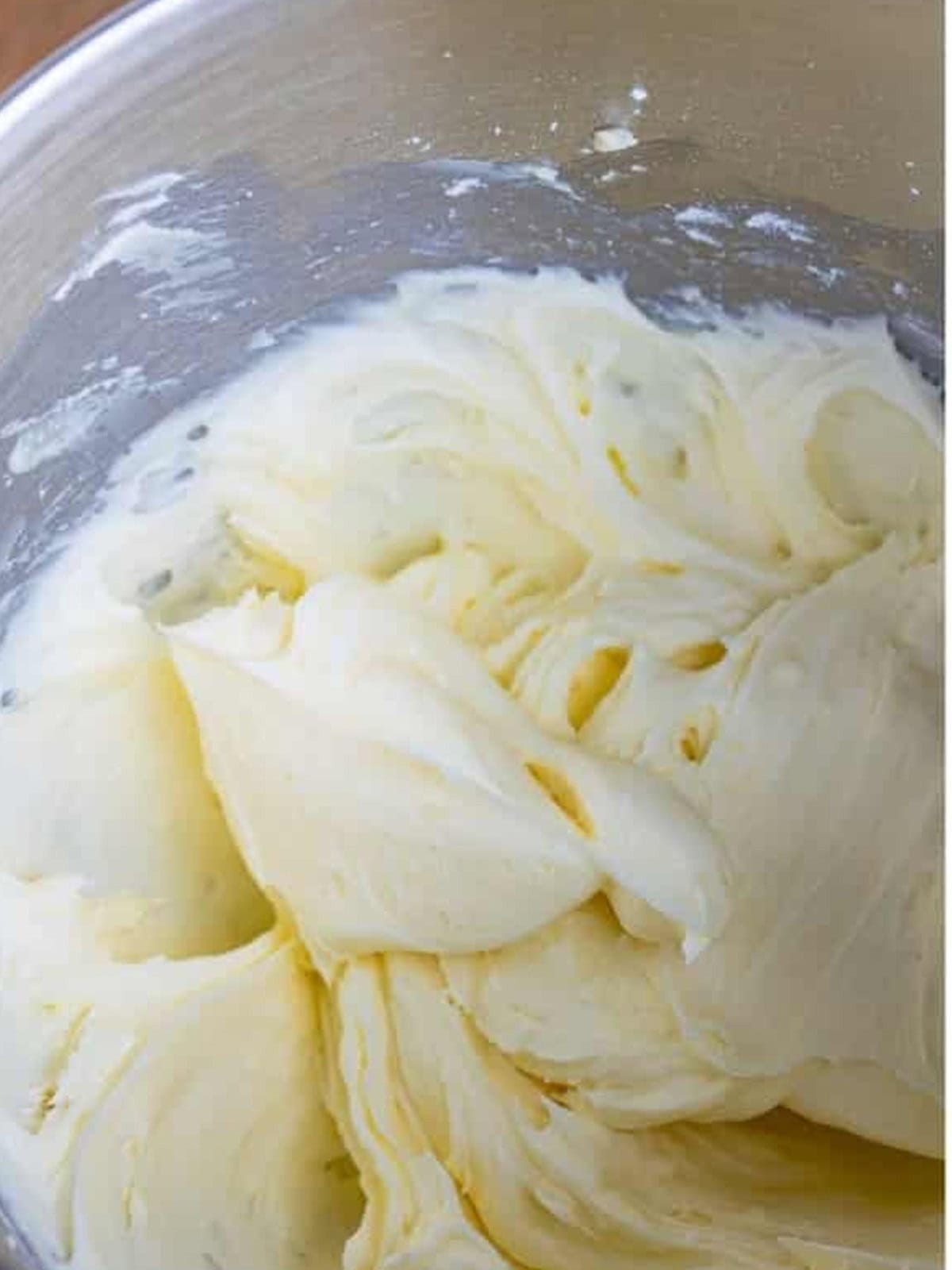 Cream cheese frosting beaten smooth in a mixing bowl.