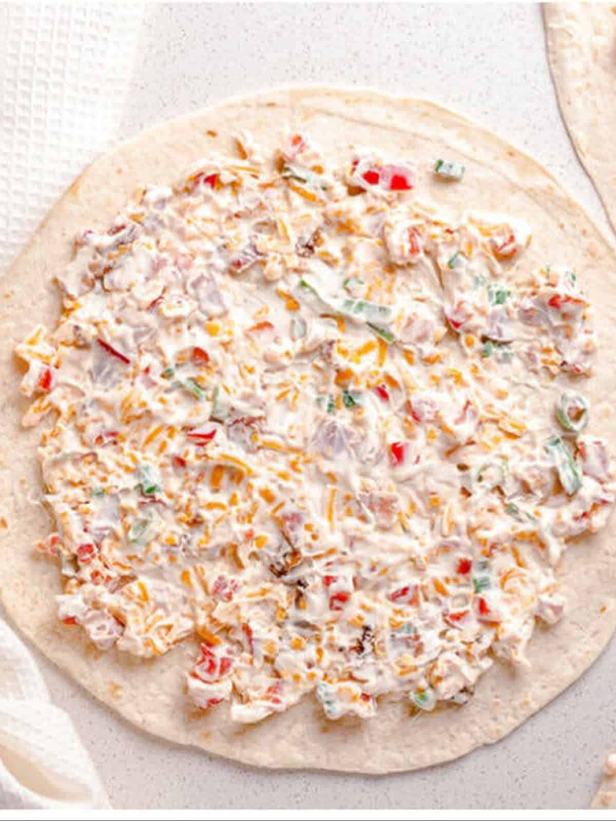 Cream cheese filling spread in a thin layer over a flour tortilla.