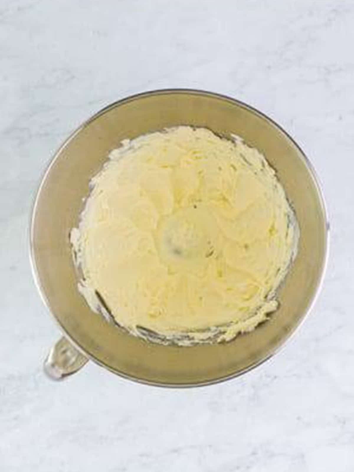 Whipping cream cheese smooth in a stand mixer bowl for cream horns filling.