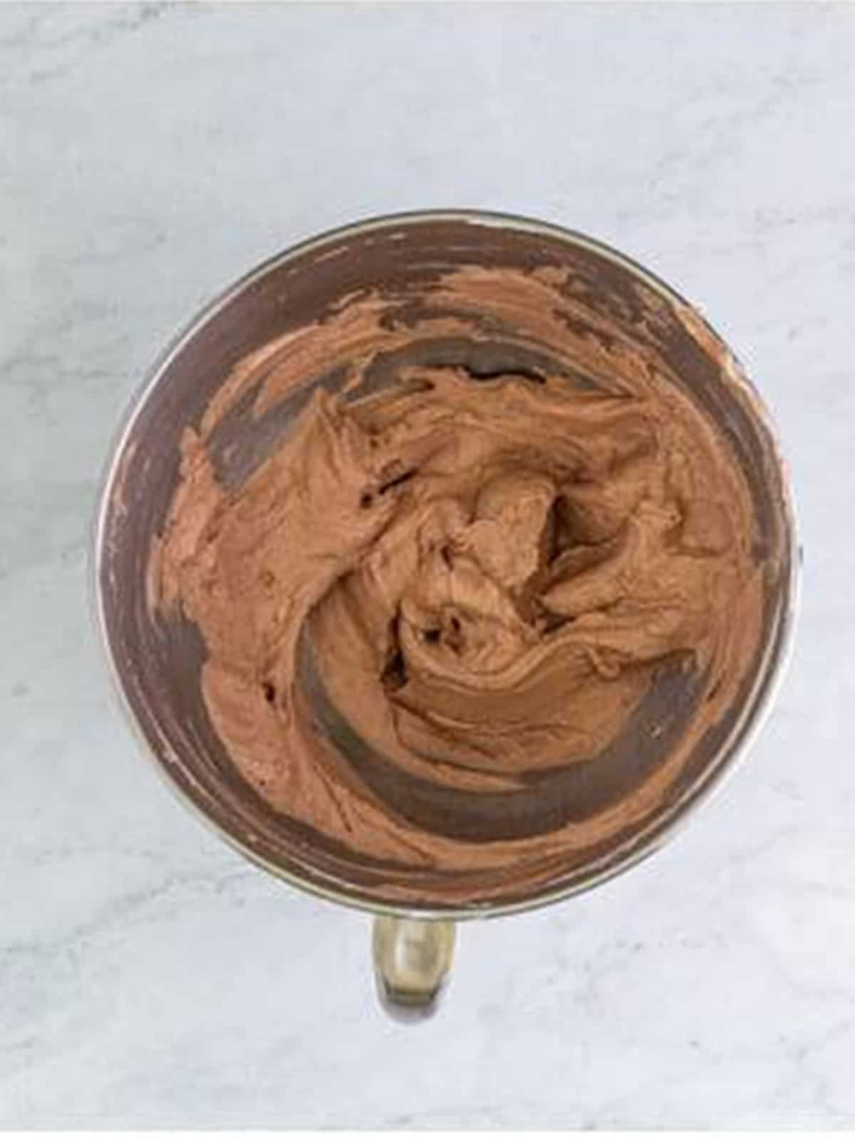 Chocolate cream horns filling mixed with cocoa powder in the mixer bowl.