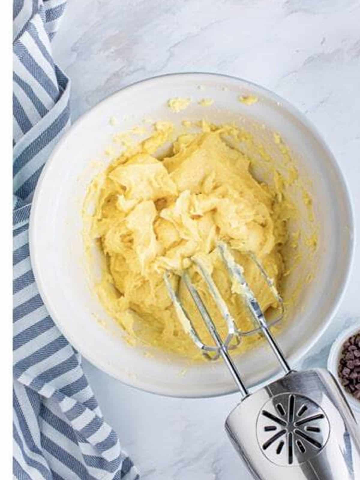 Eggs being beaten into the choux dough until smooth and glossy.