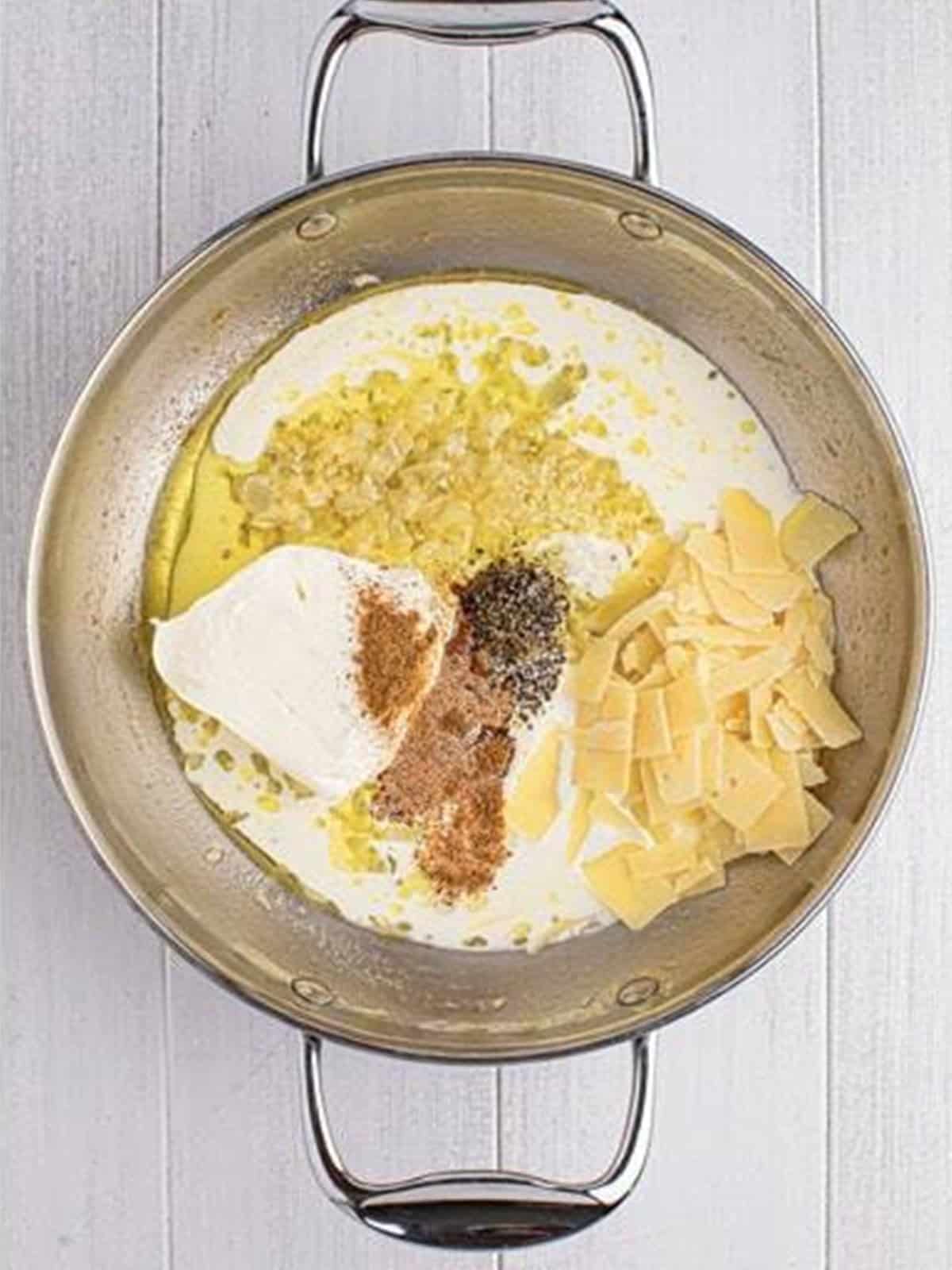 Cream cheese, heavy cream, parmesan, and seasonings added to the skillet for creamed spinach sauce.