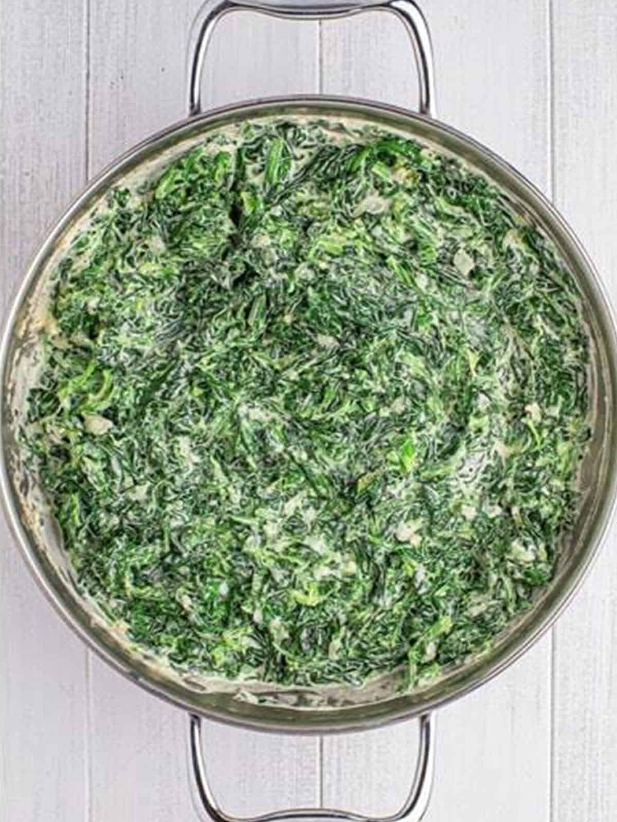 Finished creamed spinach simmered until thick and creamy in a skillet.