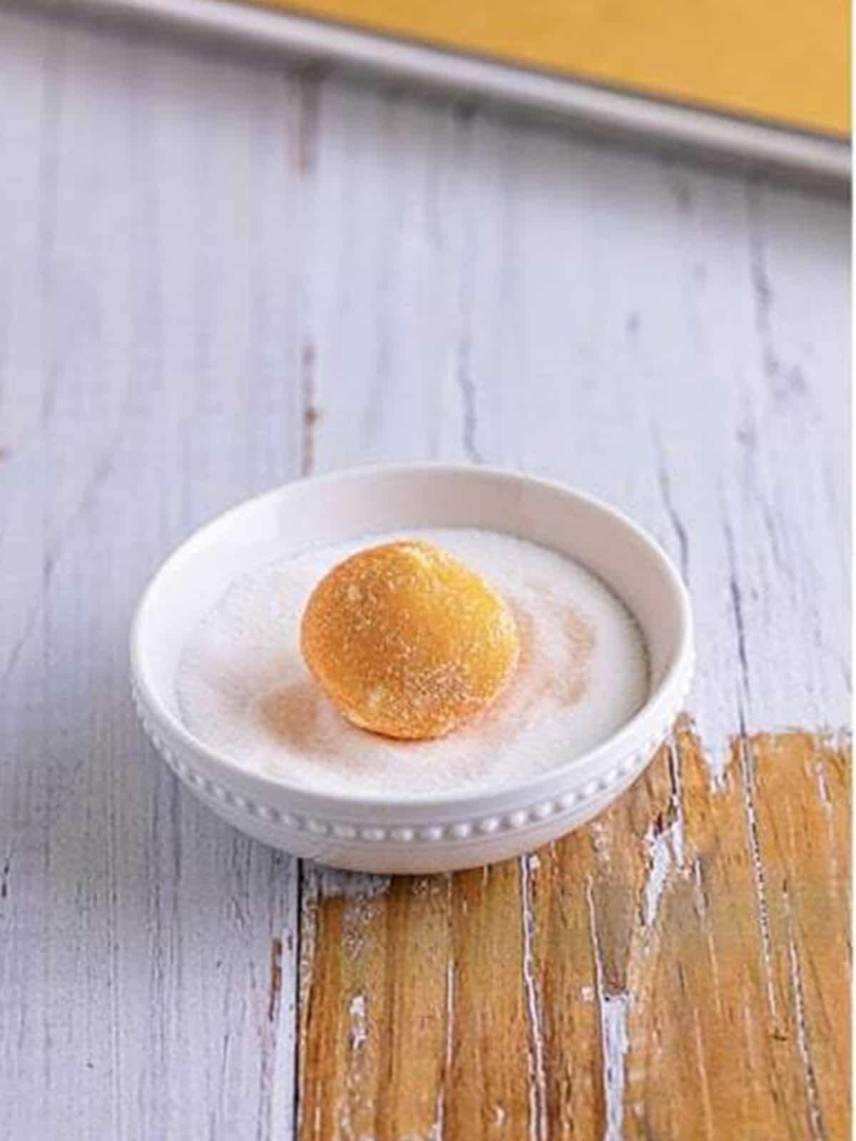 An orange creamsicle cookie dough ball rolled in granulated sugar.