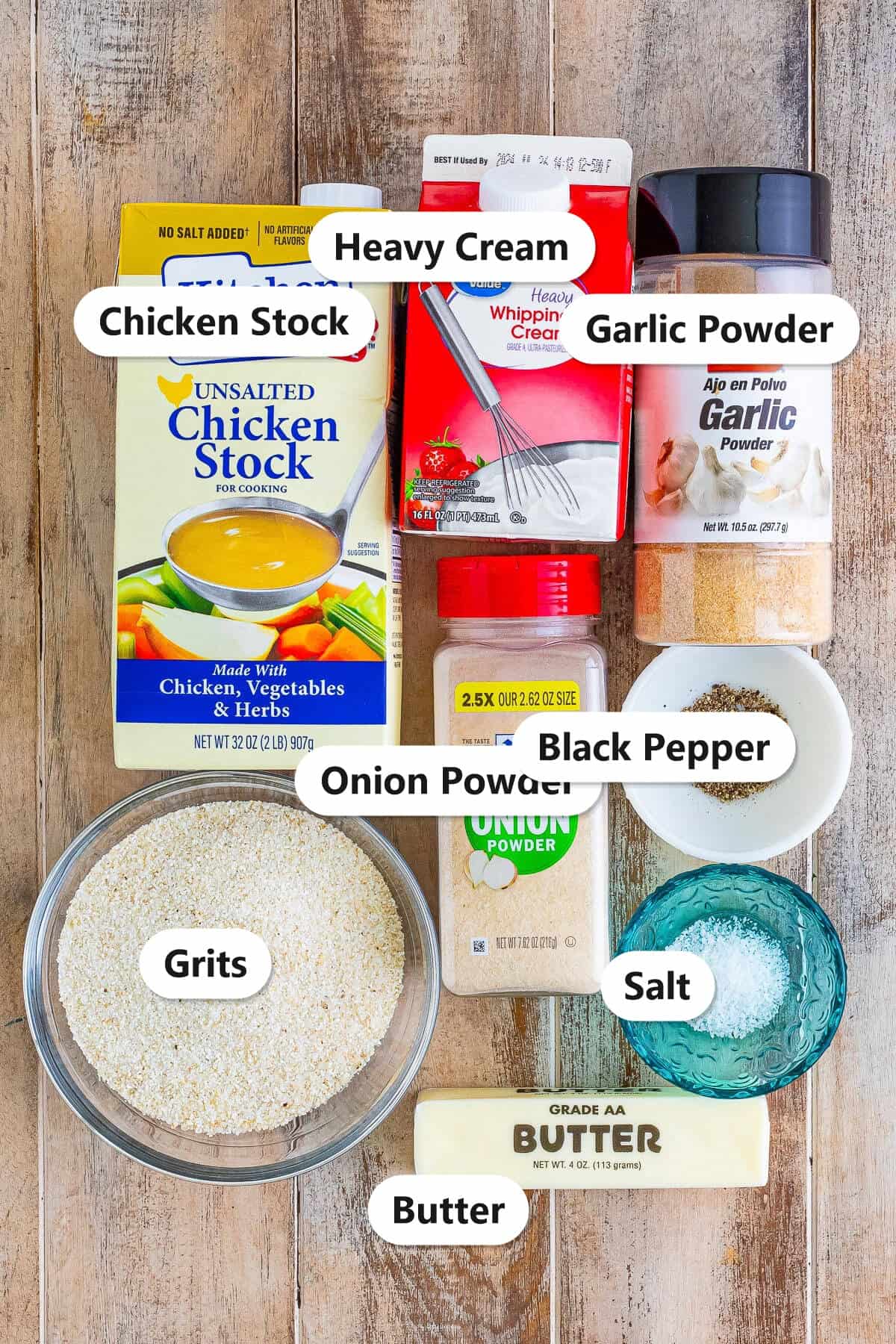 Labeled ingredients to make creamy grits including grits, chicken stock, heavy cream, butter, and seasonings.