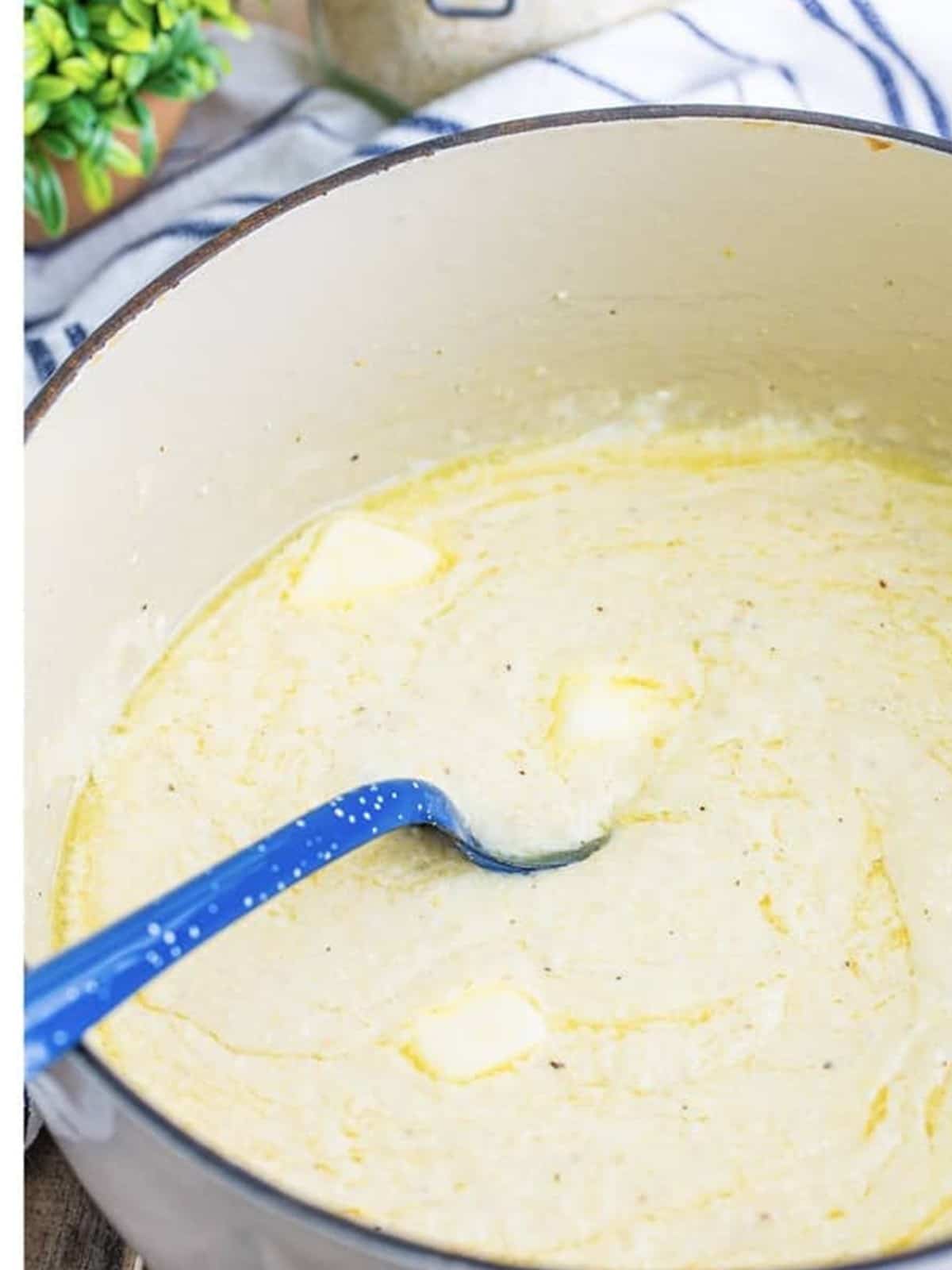 Butter stirred into the finished creamy grits with a spatula.