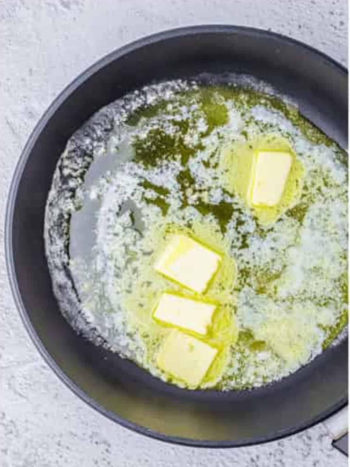 Butter melting in a large black skillet for creamy lemon shrimp.