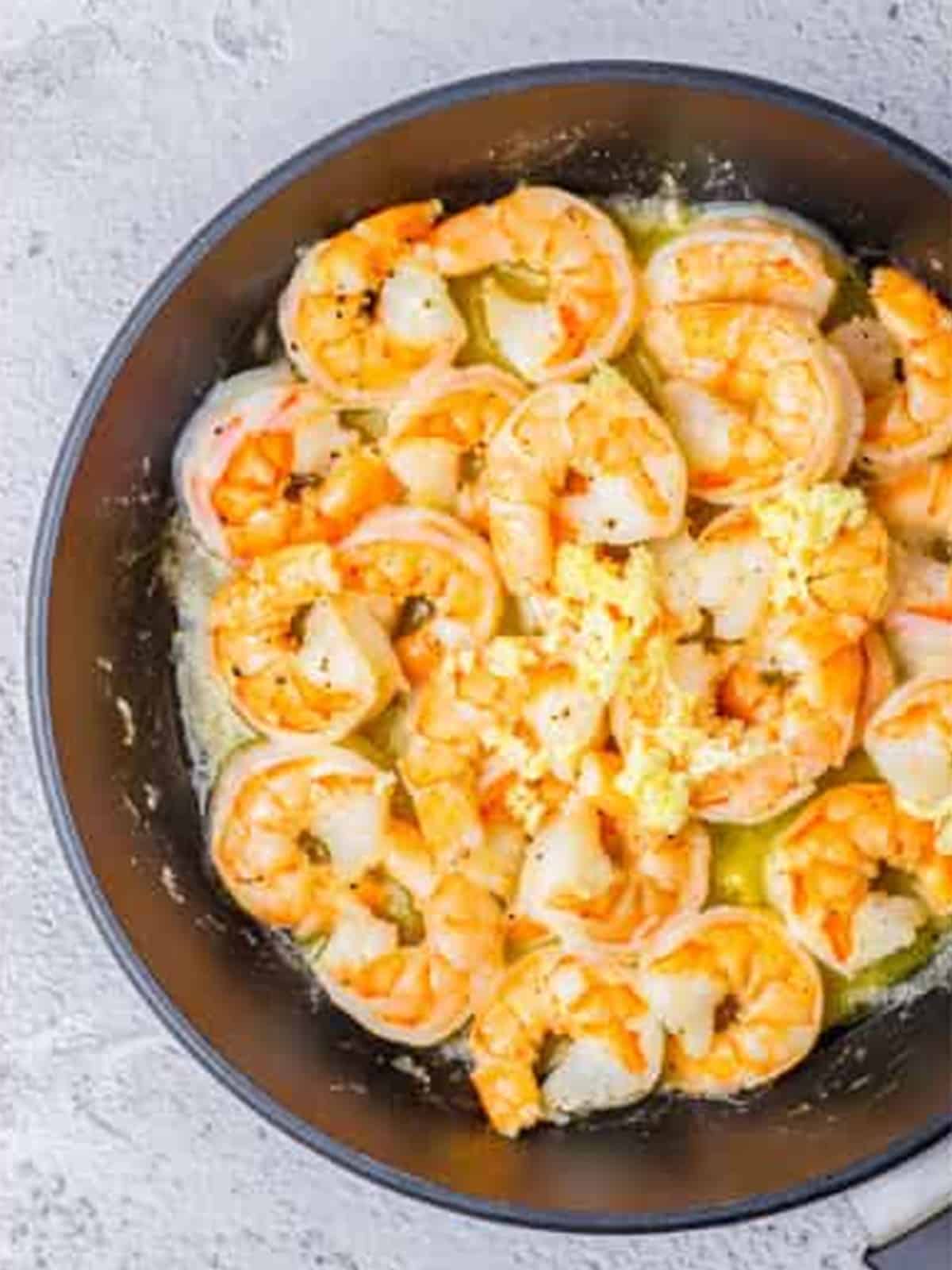 Minced garlic added to the shrimp in the skillet for creamy lemon shrimp.