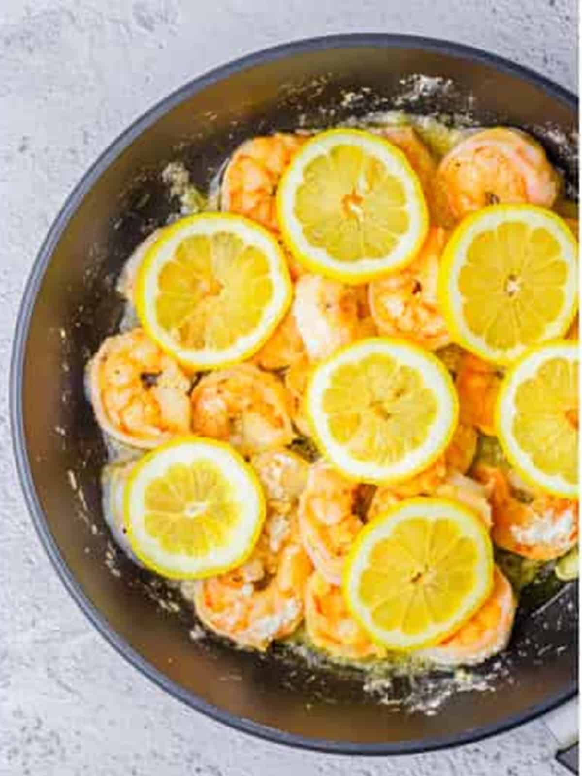 Fresh lemon slices added to the shrimp in the skillet for creamy lemon shrimp.