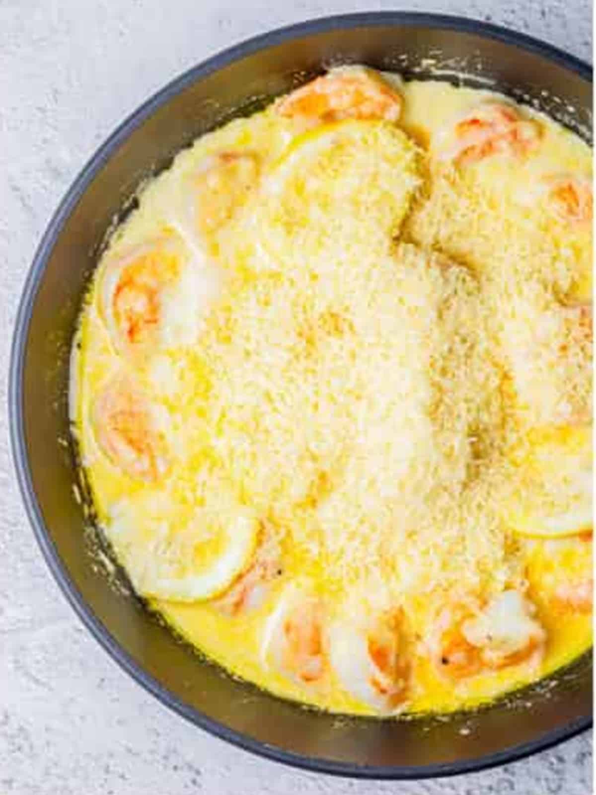 Parmesan cheese added to the creamy lemon shrimp sauce in the skillet.