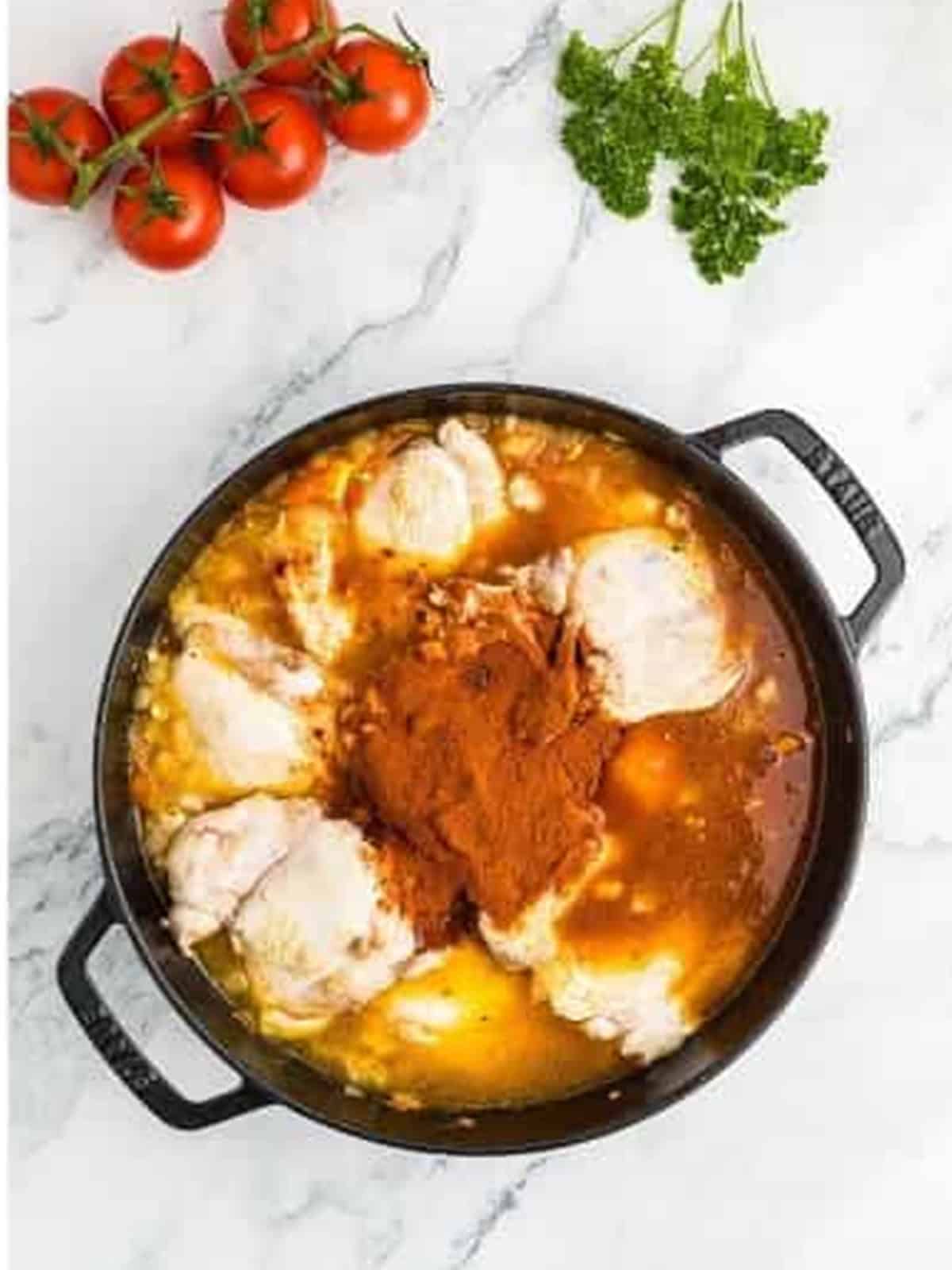 Paprika and chicken stock added to the skillet with the chicken thighs.