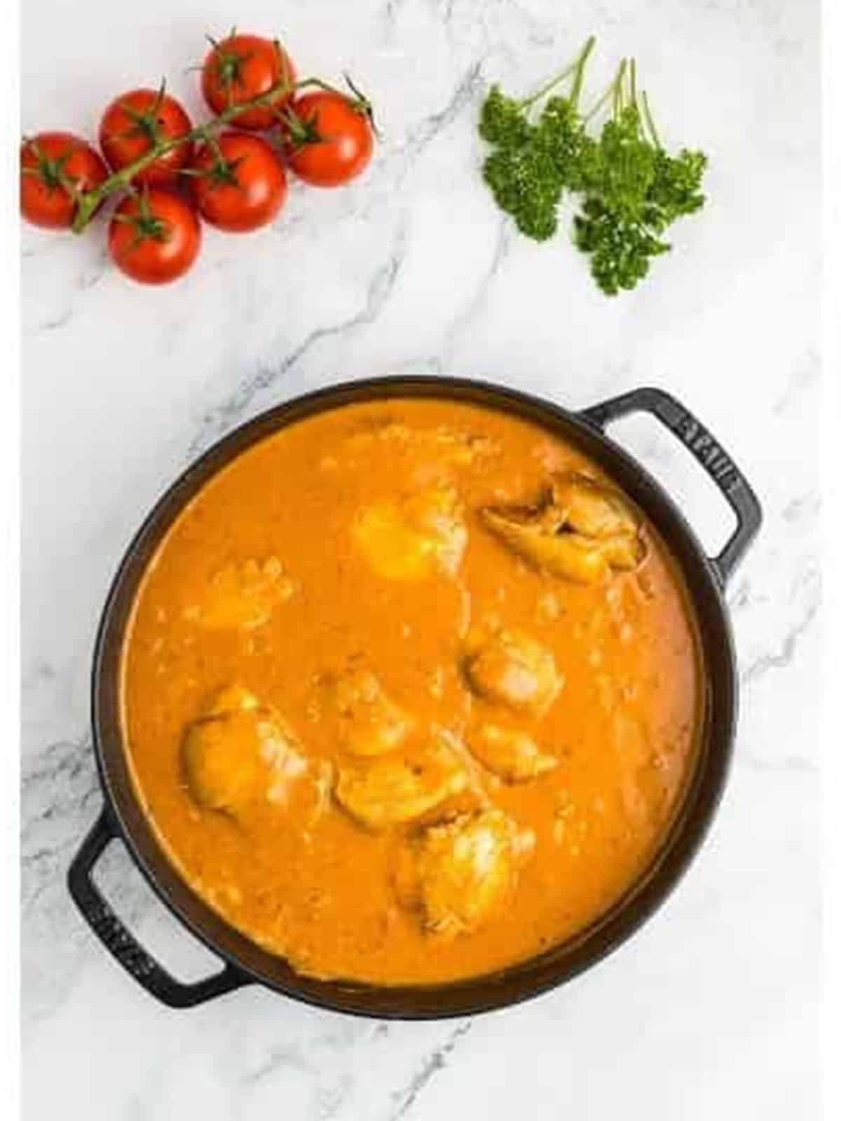 Creamy orange paprika sauce simmering with chicken thighs in the skillet.