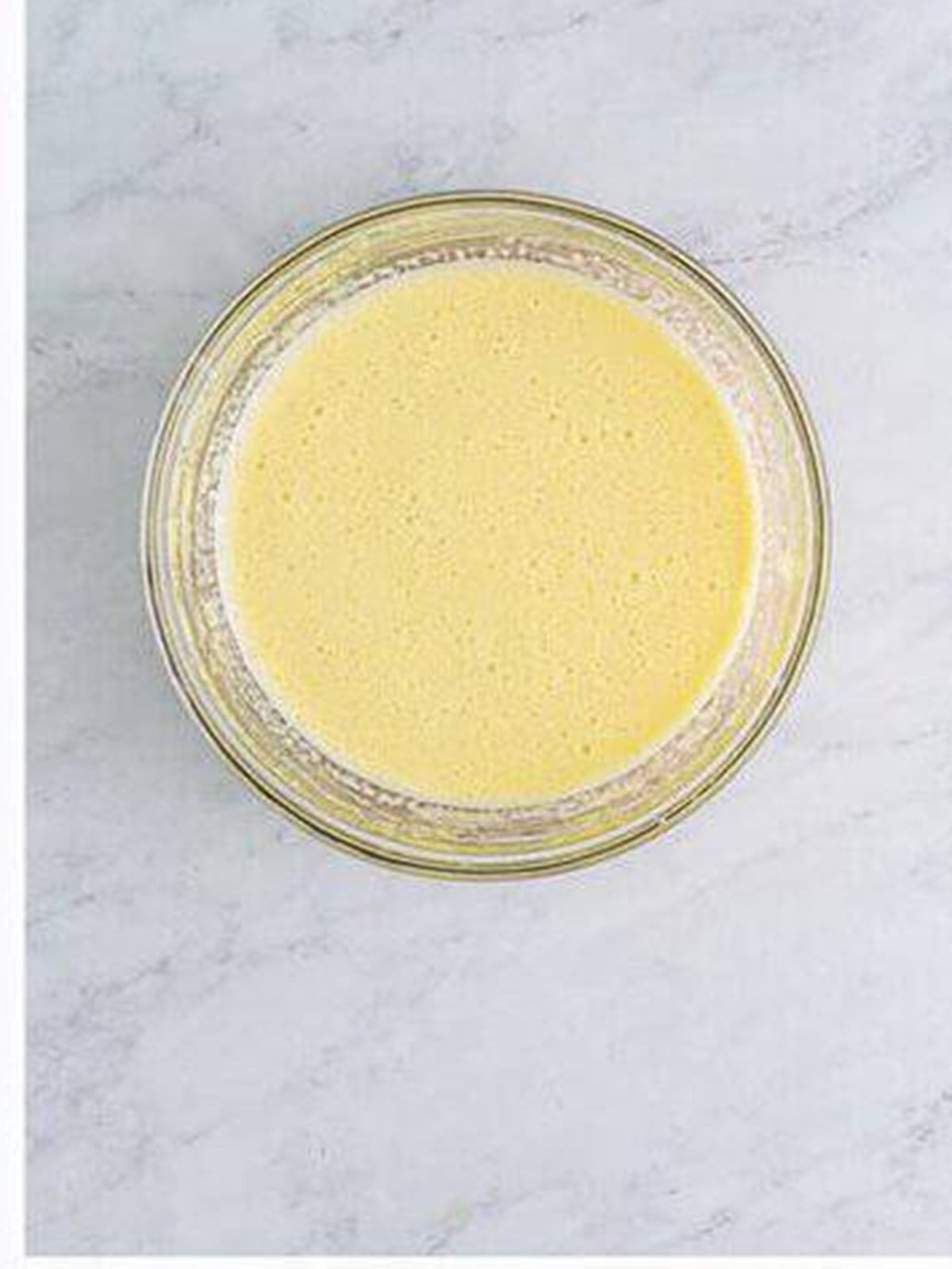 Hot cream slowly streamed into the egg yolks to temper them for creme anglaise.