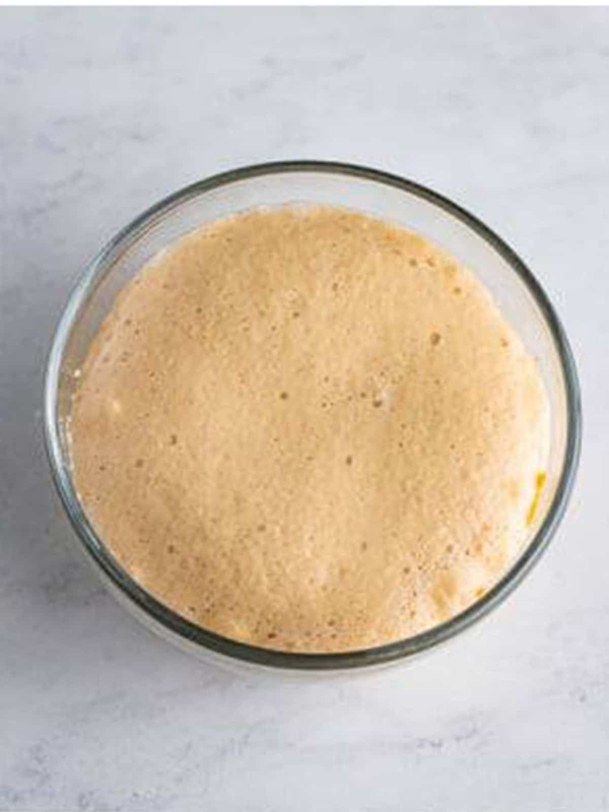 Active dry yeast blooming and turning frothy in warm water for crescent rolls.