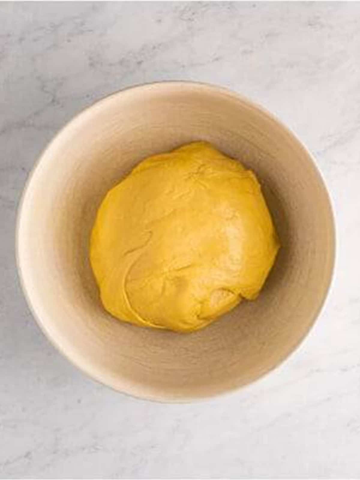 Crescent roll dough risen and doubled in size in a bowl.
