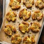 Crispy golden smashed potatoes on a parchment lined sheet pan fresh from the oven.
