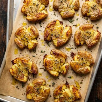 Crispy golden smashed potatoes on a parchment lined sheet pan fresh from the oven.