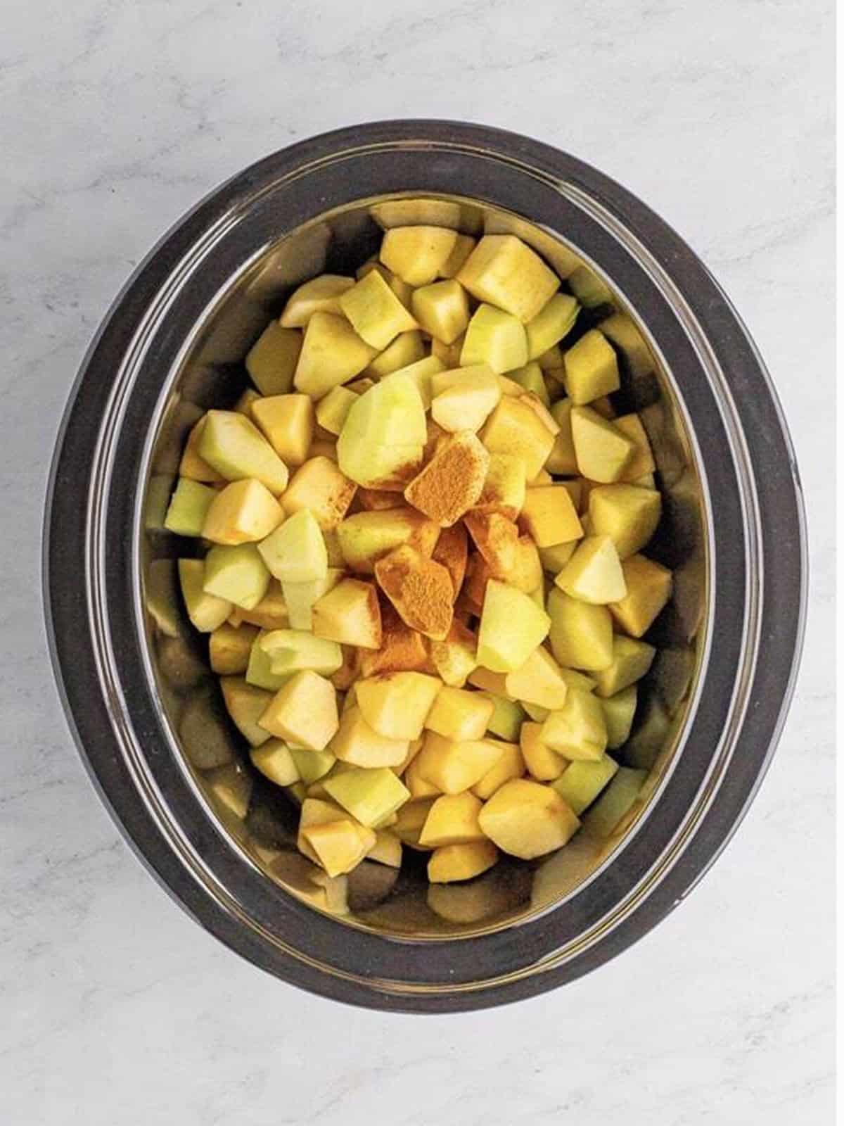 Peeled and cubed apples in a slow cooker.