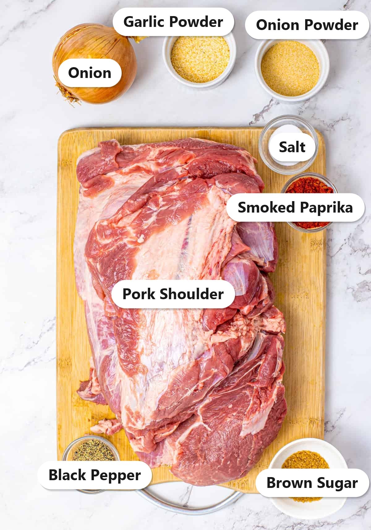 Labeled ingredients to make crock pot pulled pork including pork shoulder, sweet onion, garlic powder, onion powder, brown sugar, smoked paprika, salt, and black pepper.
