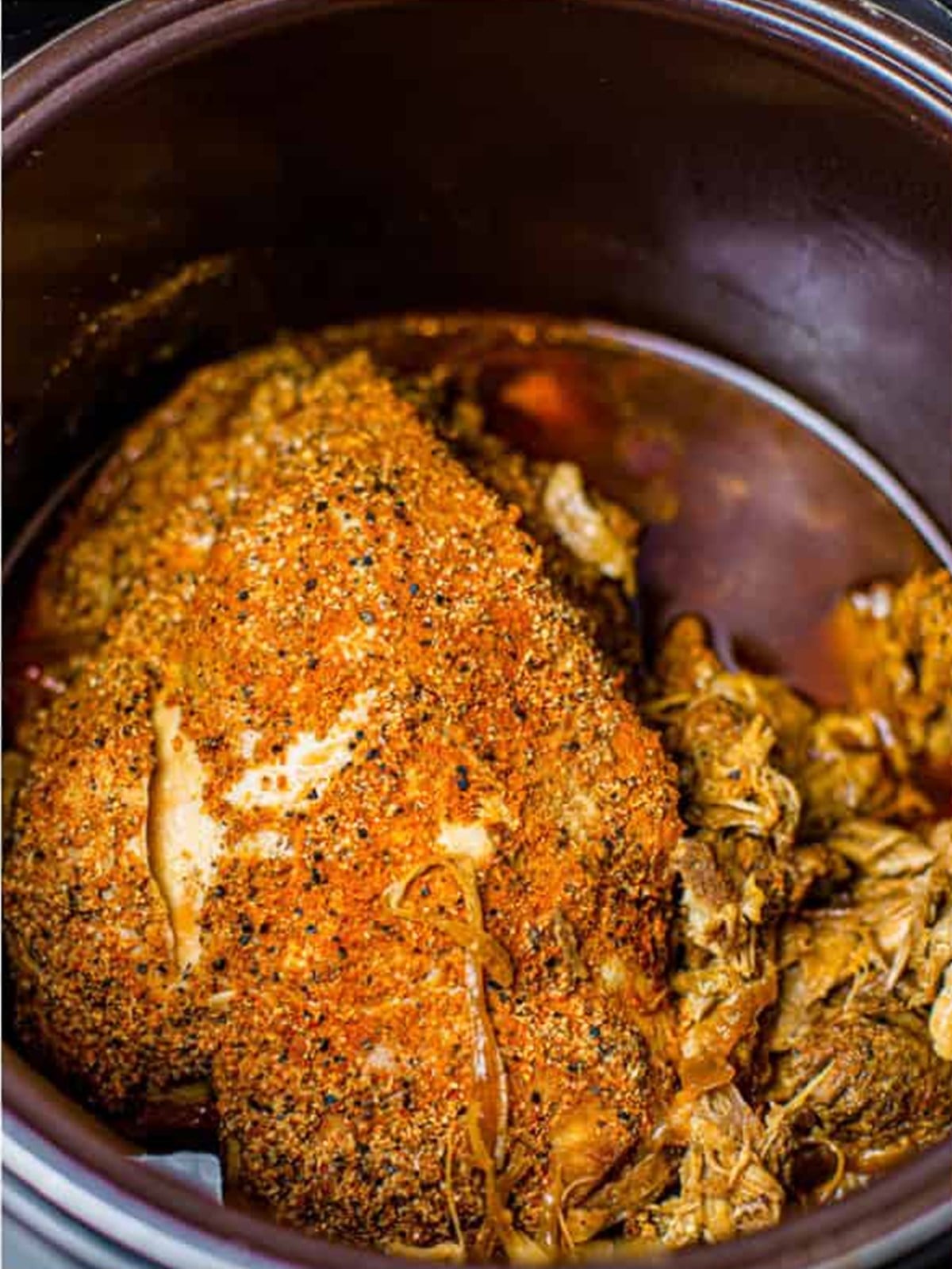Fully cooked pork shoulder in the slow cooker ready to shred.