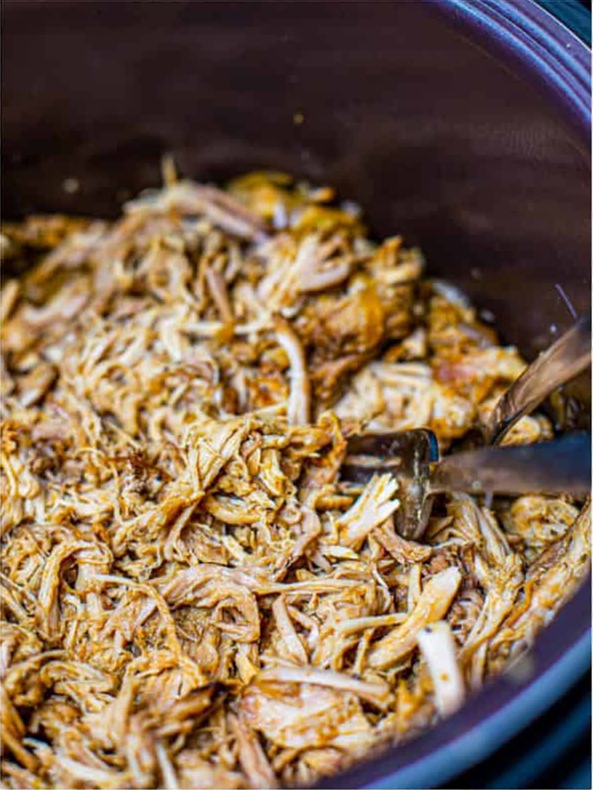 Shredded crock pot pulled pork mixed with onions and juices in the slow cooker.