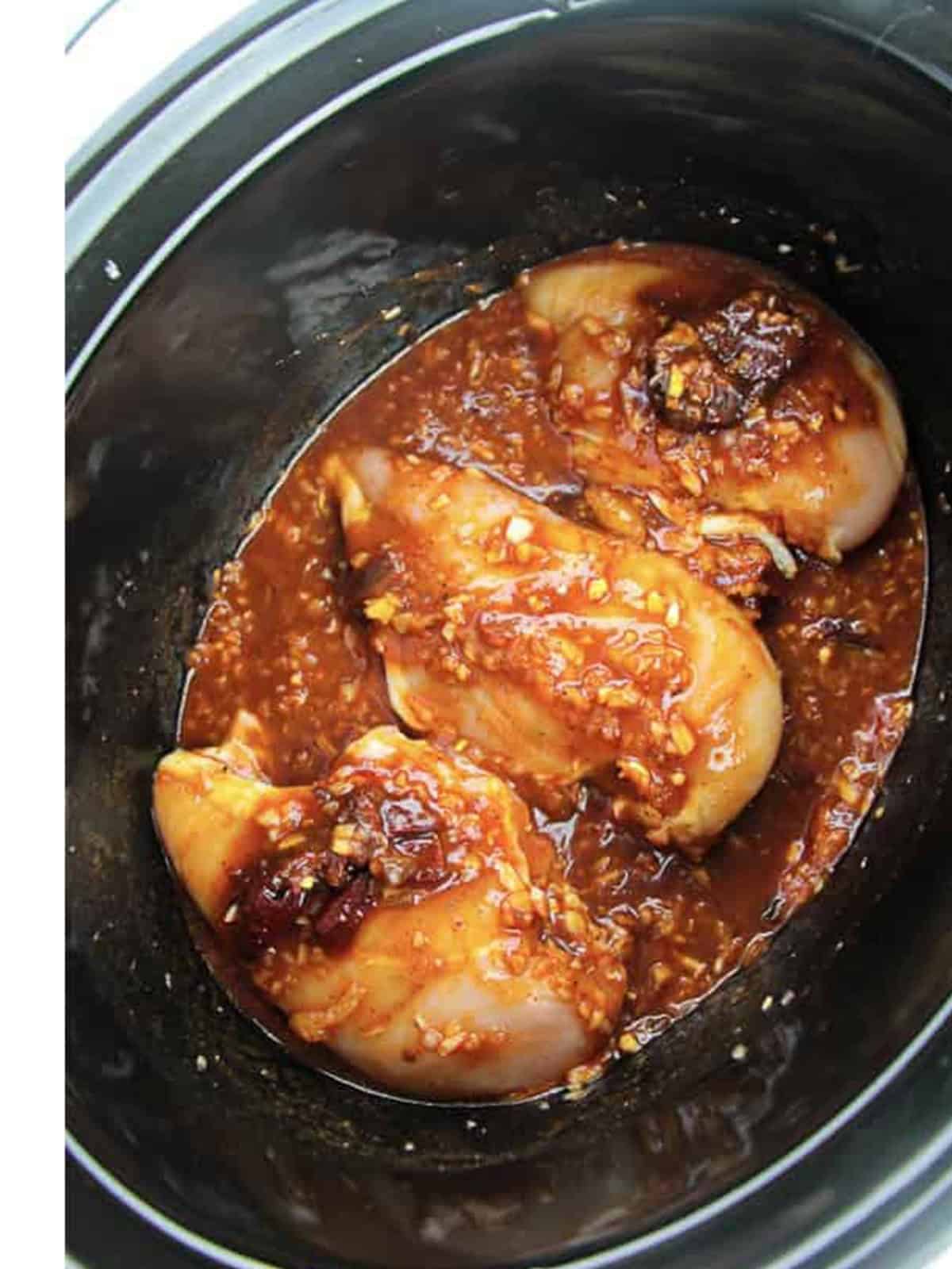 Chicken breasts added to the chipotle sauce in a crockpot.