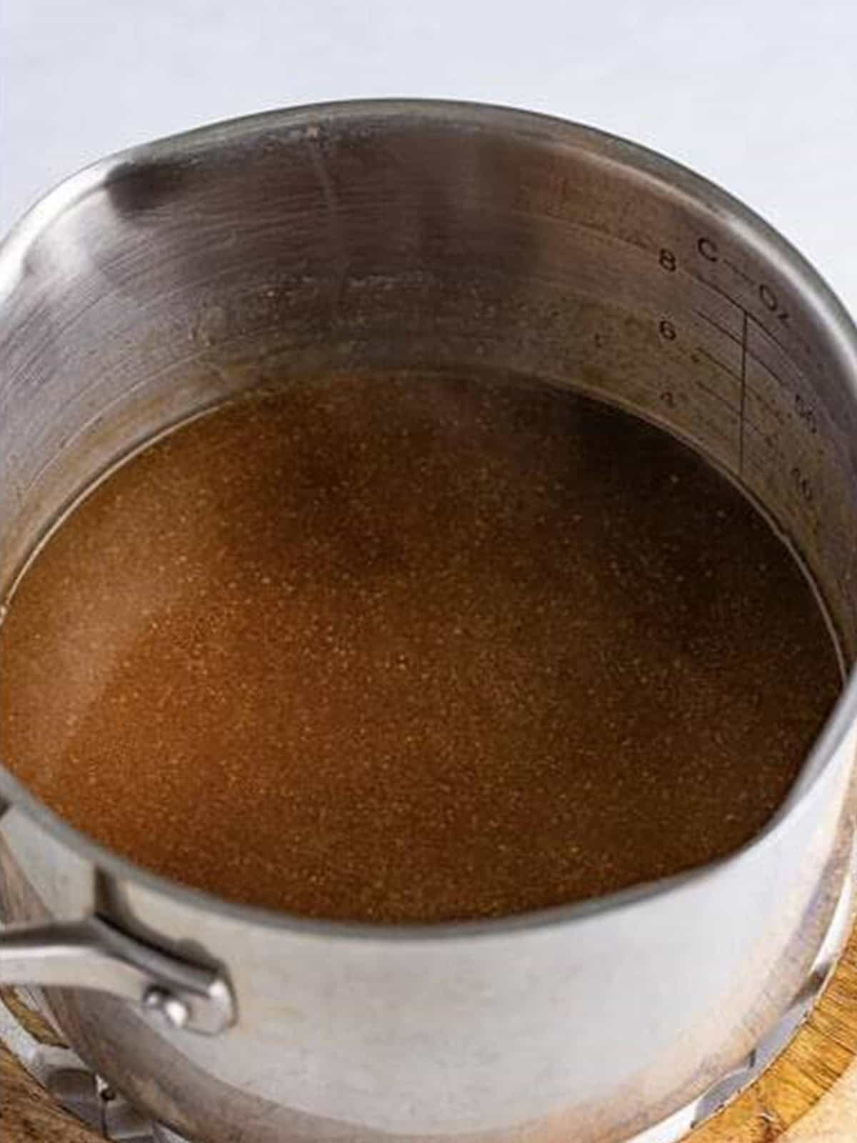 Strained gravy simmering in a pot before thickening with cornstarch slurry.