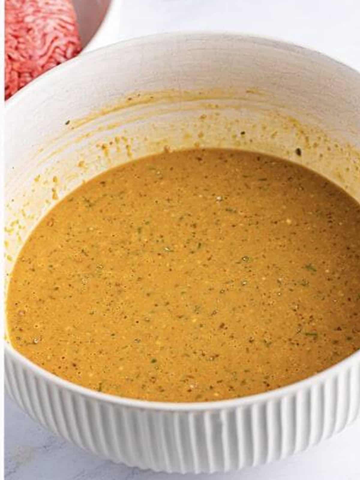 Wet base whisked smooth in a white bowl for Mississippi crockpot meatloaf.