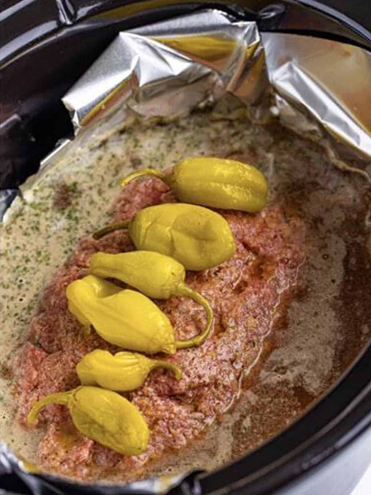 Pepperoncini peppers placed on top of the crockpot meatloaf before cooking.