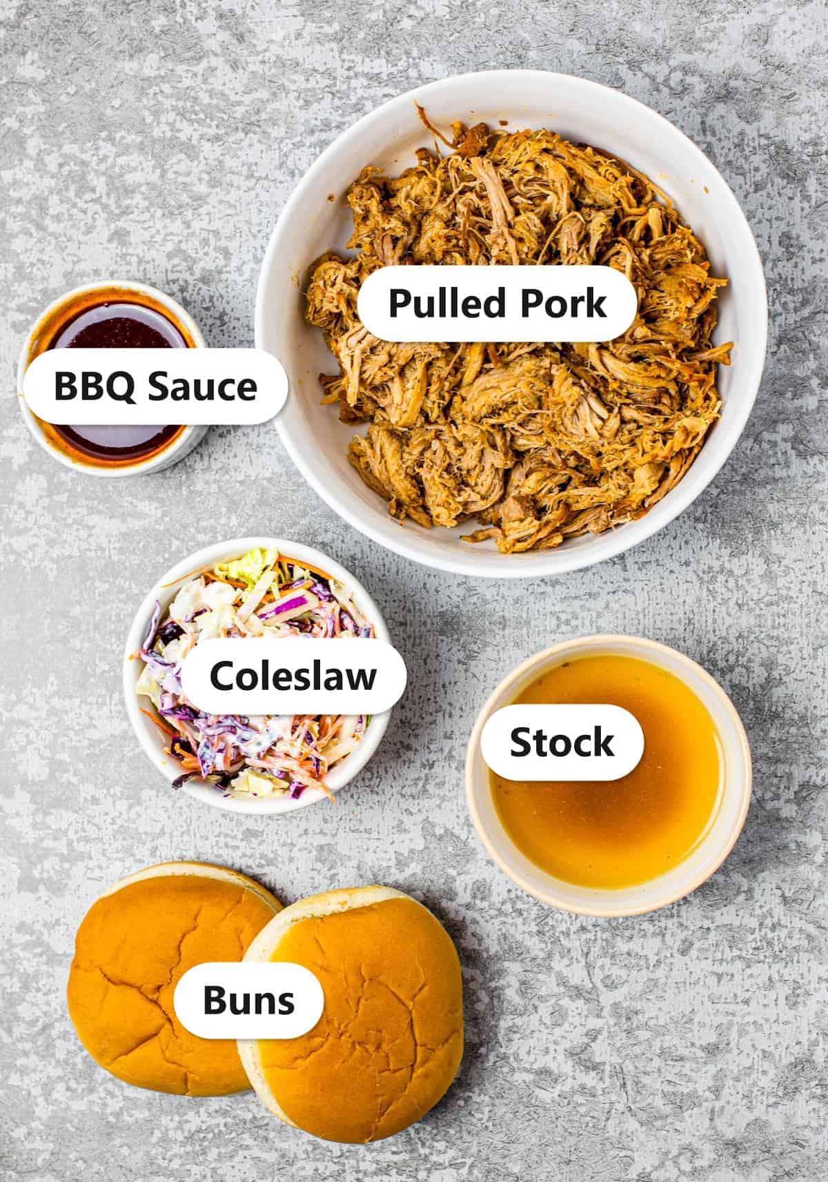 Labeled ingredients for crockpot pulled pork sandwiches including pulled pork, BBQ sauce, coleslaw, stock, and buns.