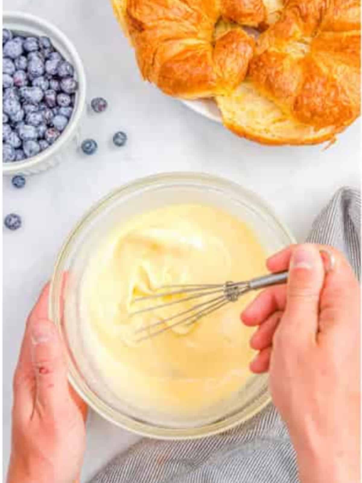Whisking together eggs, heavy cream, vanilla, and maple syrup into a smooth custard.