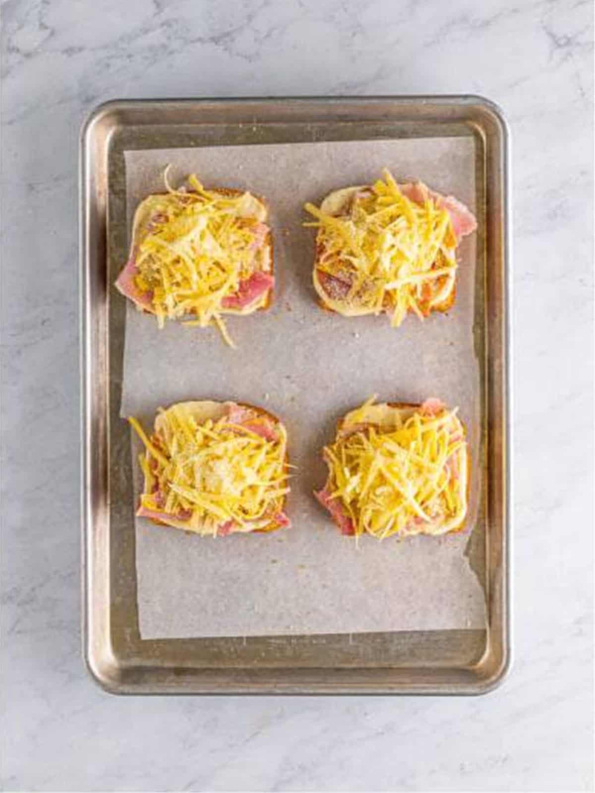 Shredded Gruyere and parmesan added over the ham on croque monsieur.