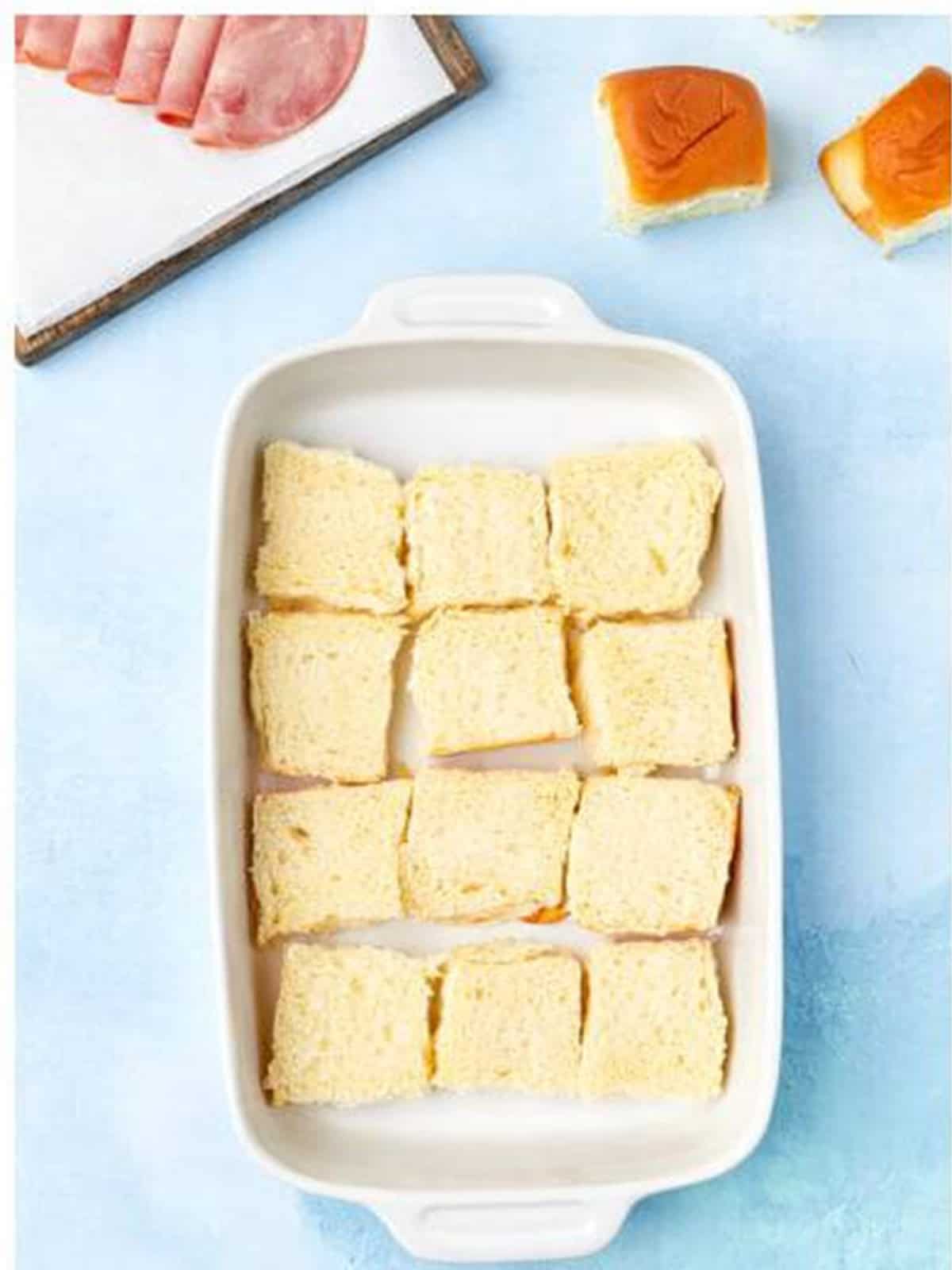 Hawaiian roll bottoms placed in a baking dish for Cuban sliders.