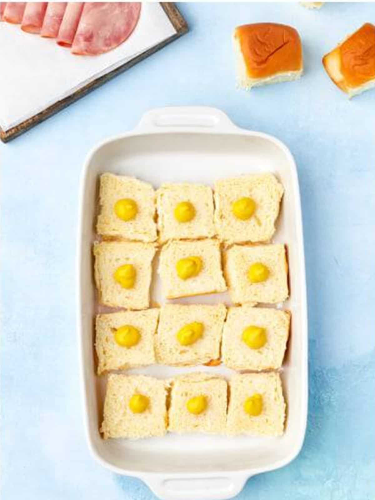 Yellow mustard squeezed onto the roll bottoms for Cuban sliders.