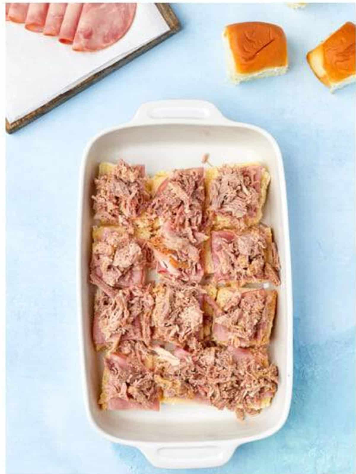 Pulled pork added over the ham for baked Cuban sliders.