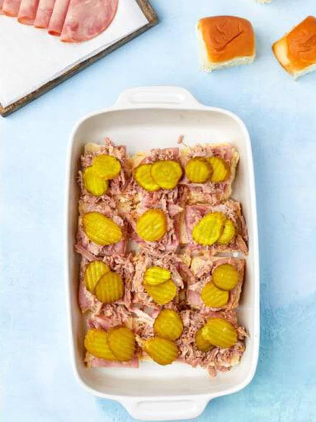 Pickle chips and Swiss cheese added on top of the pork for Cuban sliders.