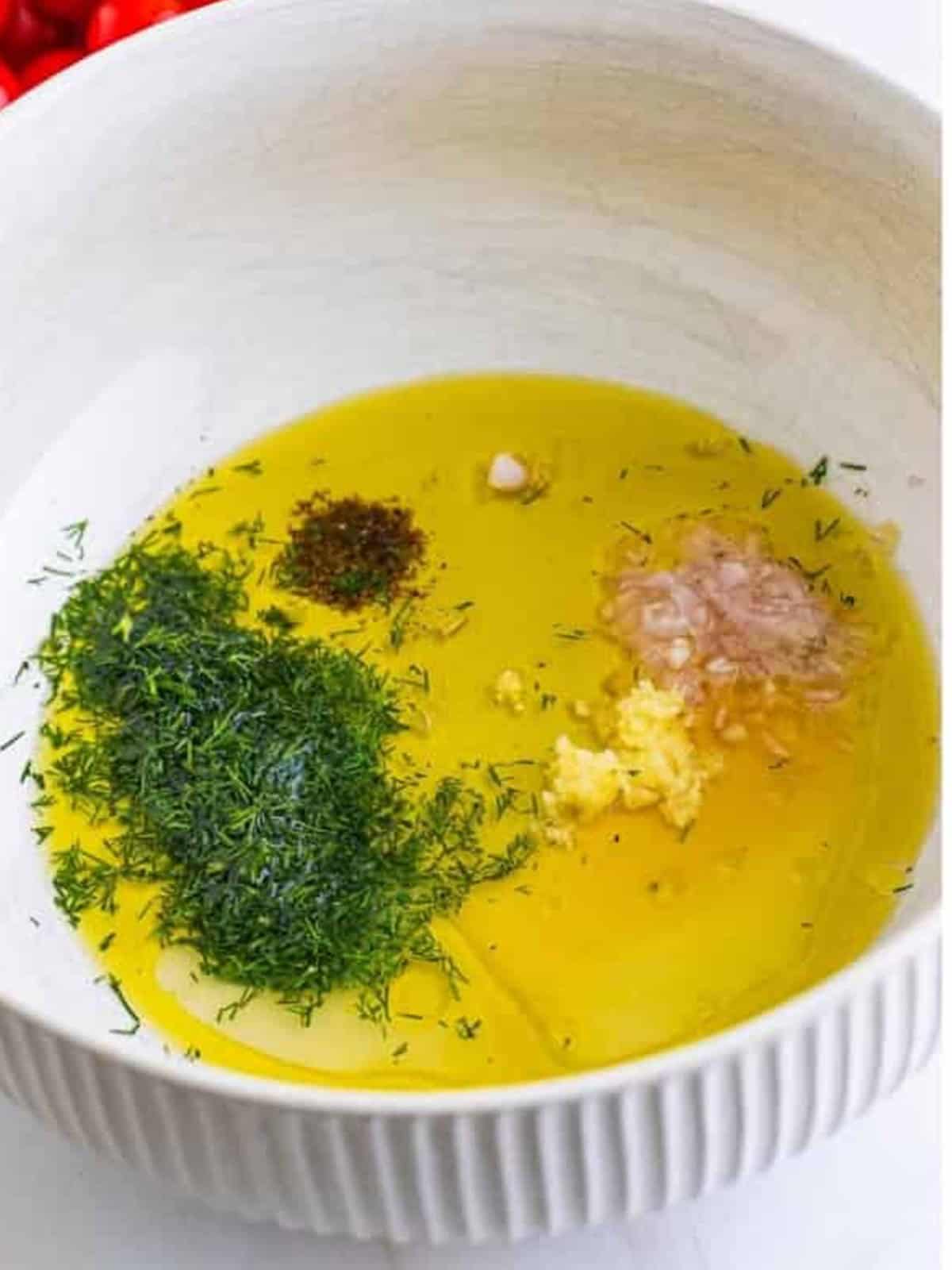 Olive oil, lemon, dill, and seasonings added to a bowl to make the dressing.