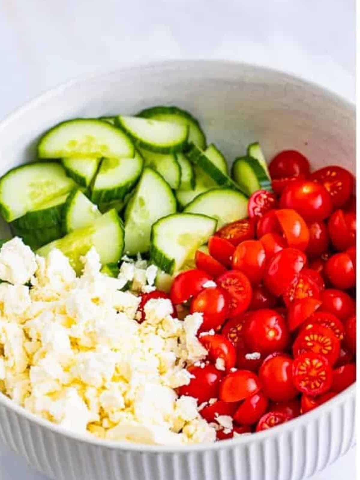 Sliced cucumber, cherry tomatoes, and crumbled feta added to the dressing.